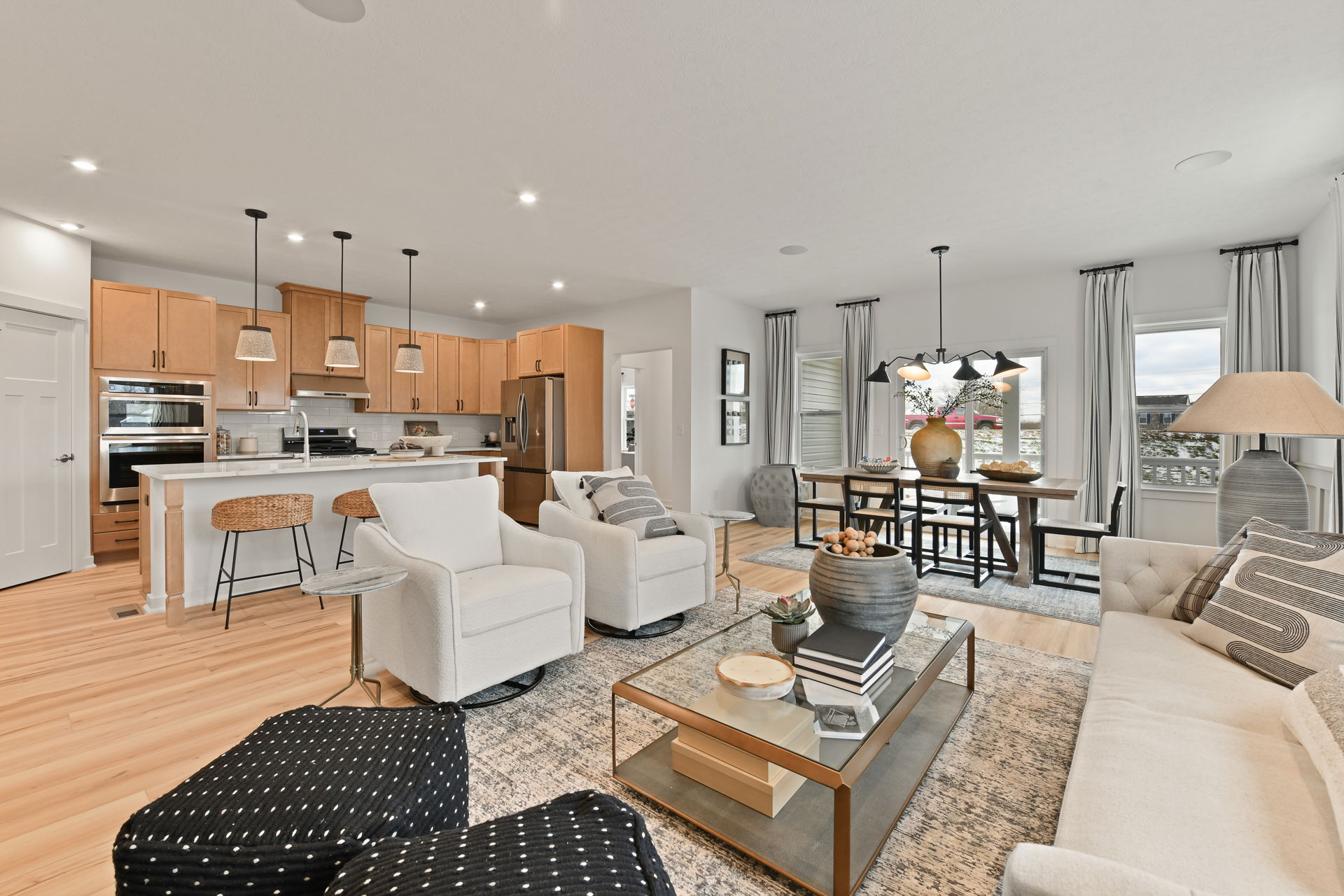 Modern open-concept living room and kitchen with neutral tones, featuring stylish furniture and decor.
