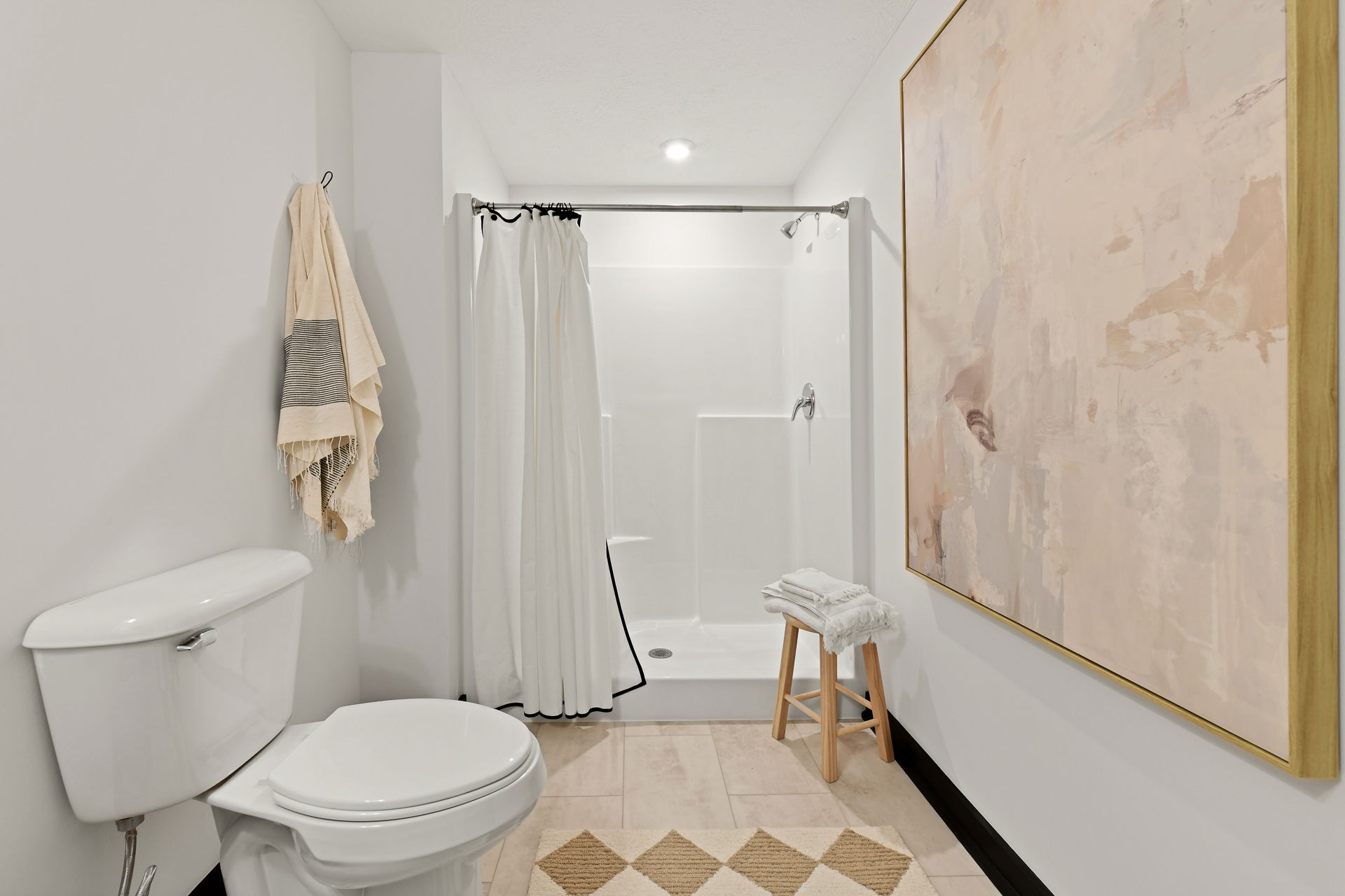 Elegant modern bathroom featuring a walk-in shower, toilet, abstract wall art, and towel accents.