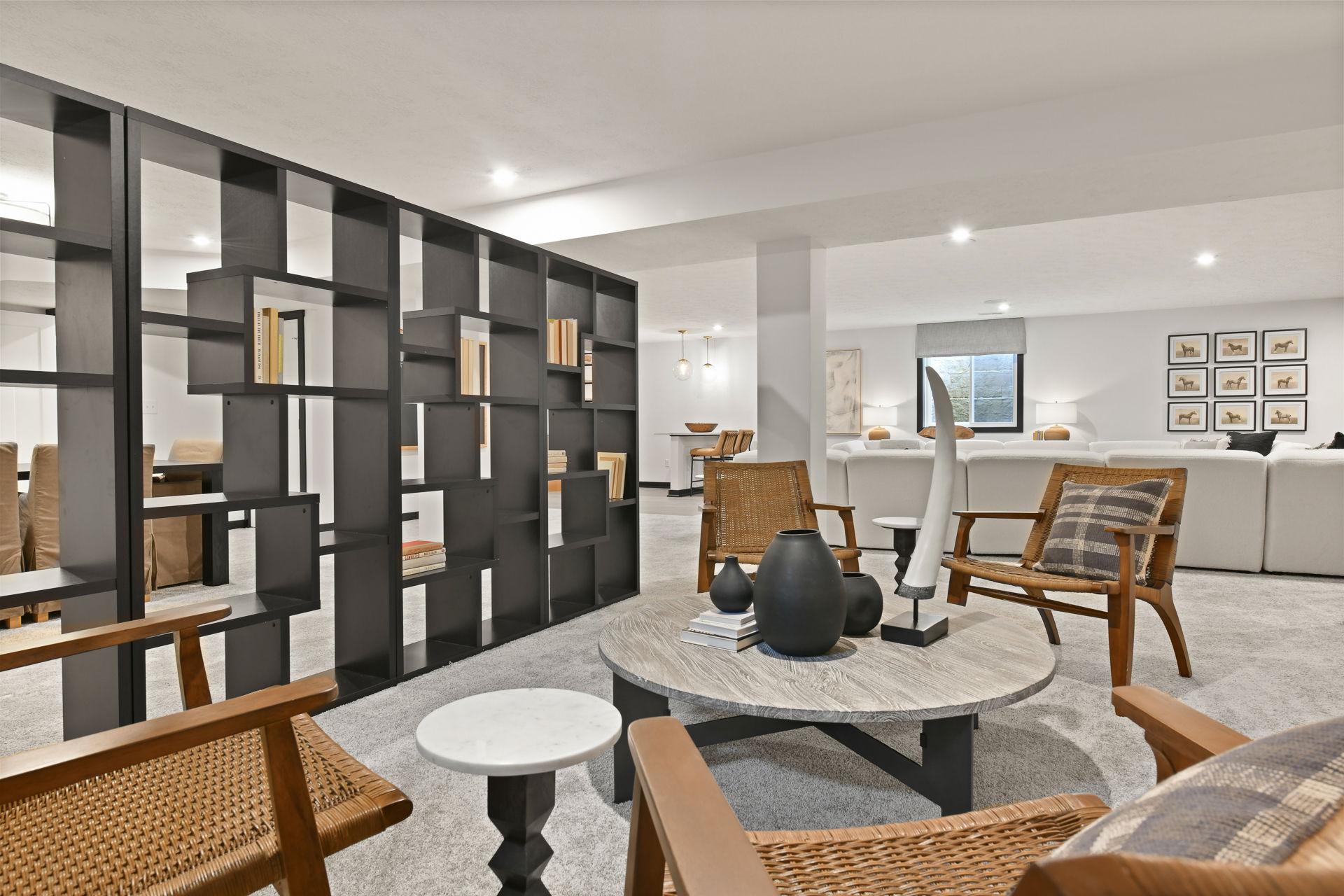 Modern basement living area with stylish wooden furniture, a large sectional sofa, decorative shelving, and elegant decor elements.