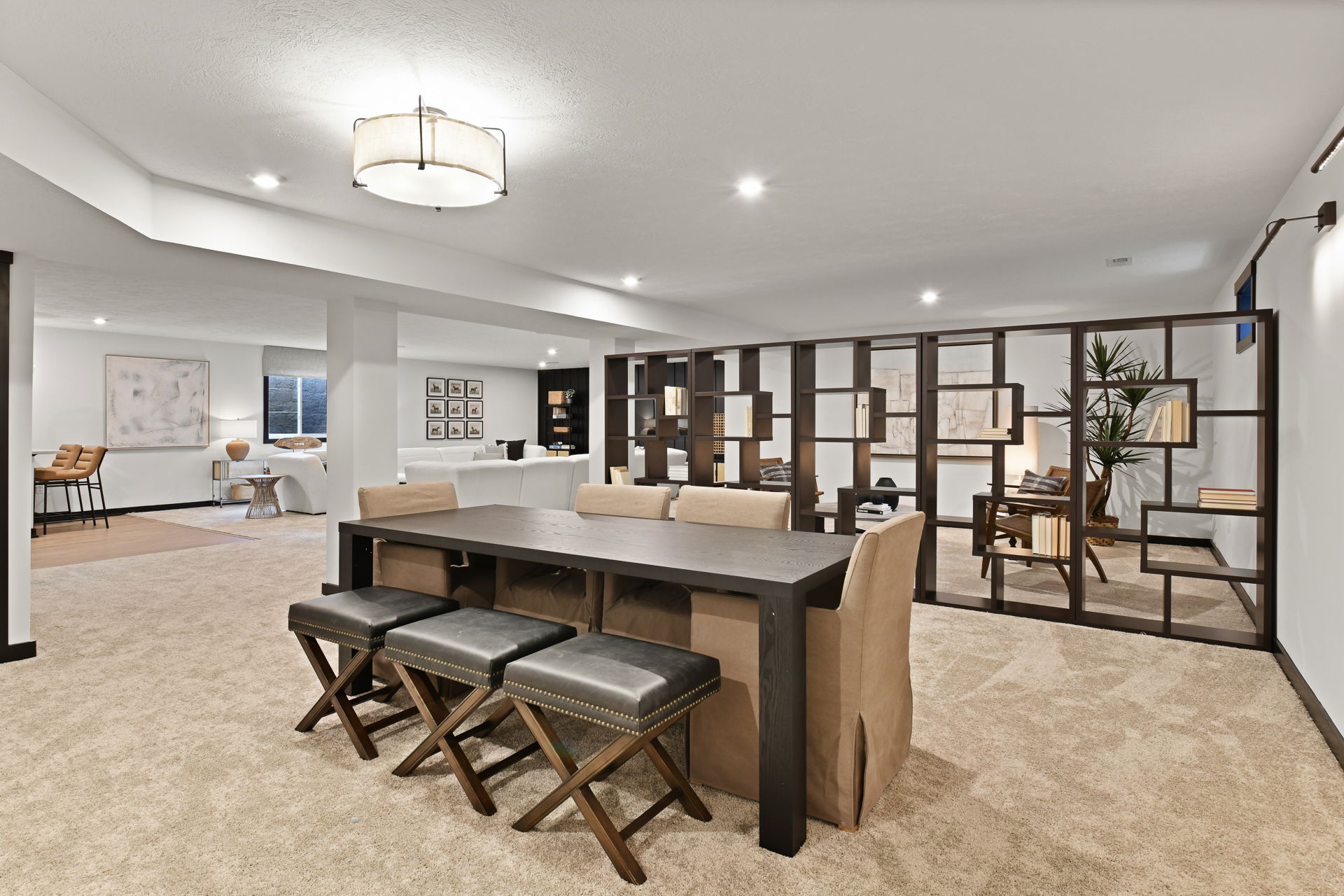 Modern open-concept basement with elegant furniture, bookshelf partition, and neutral decor.