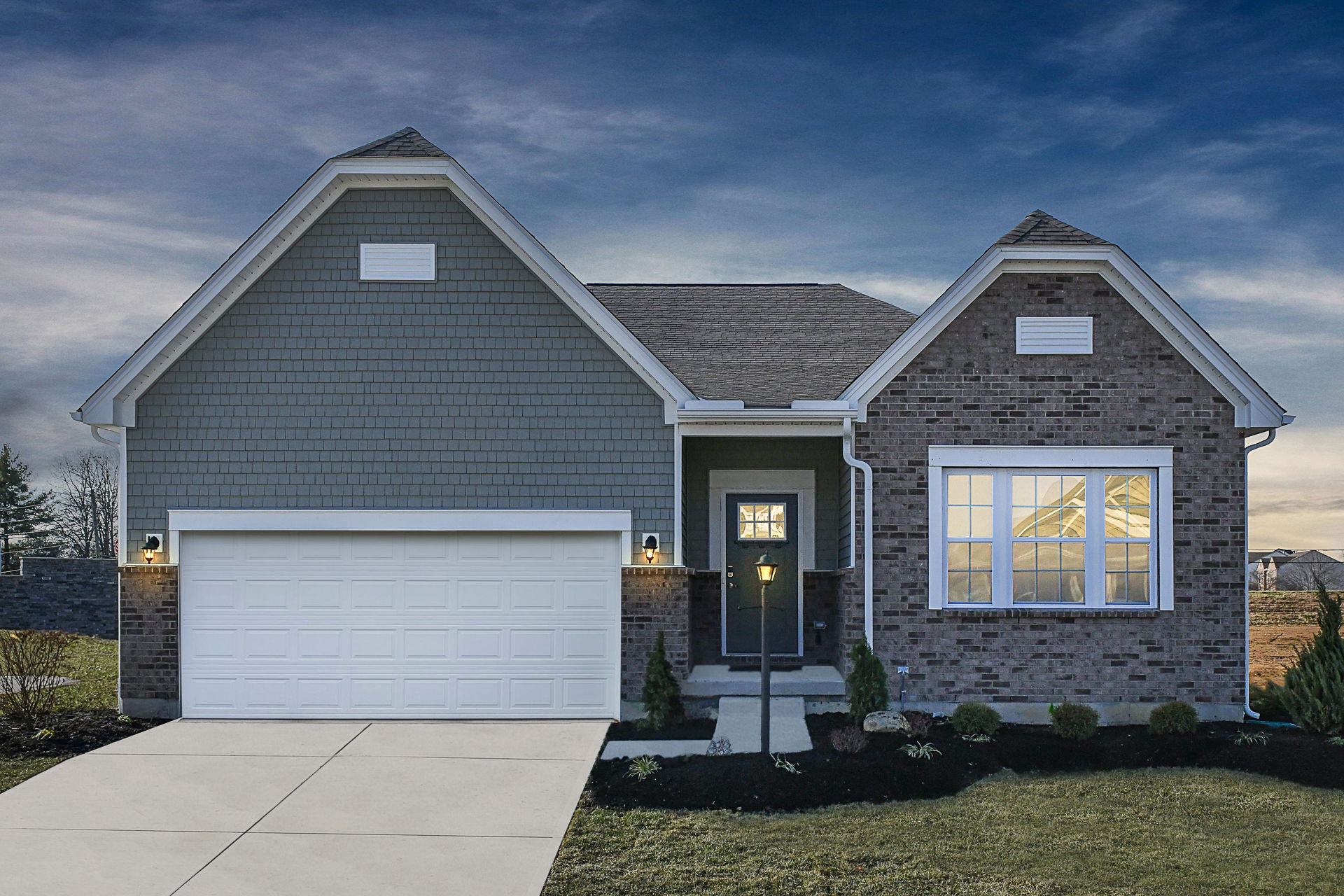 Modern single-story brick house with a garage and front yard, set against a twilight sky.