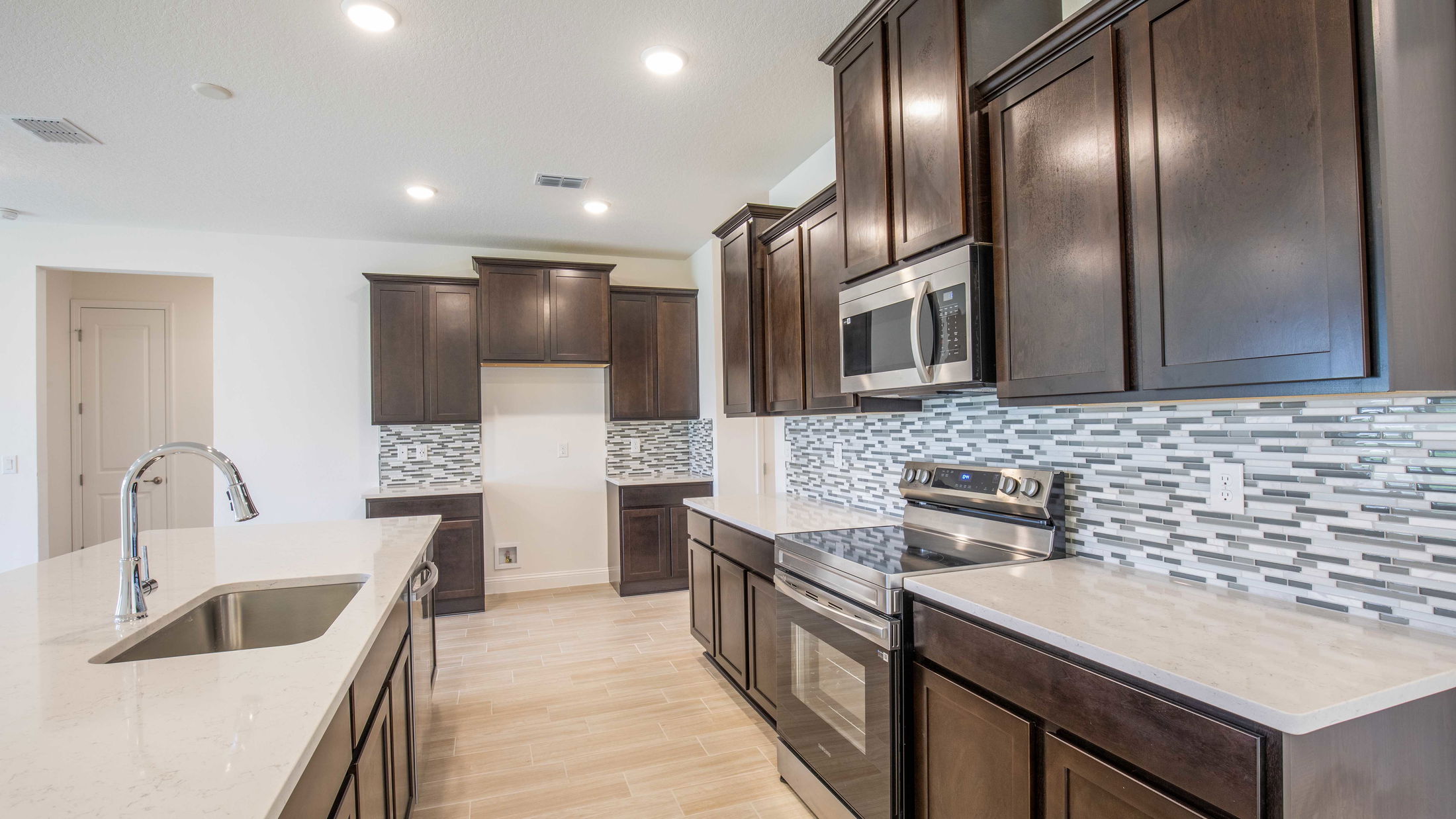 Modern kitchen with dark wood cabinets, stainless steel appliances, and a stylish mosaic tile backsplash.