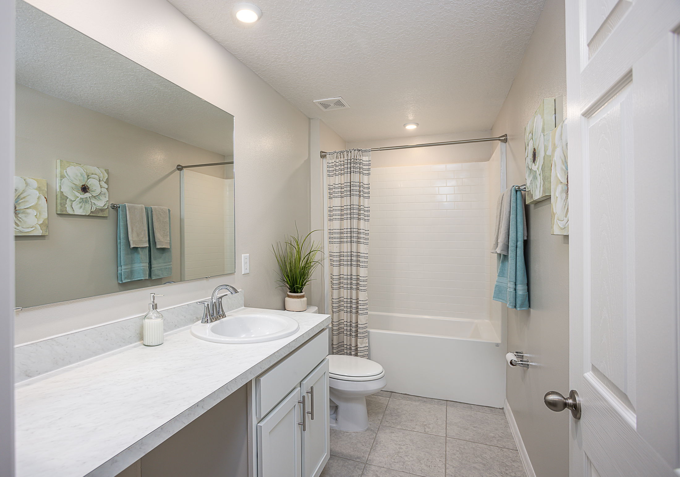 Modern bathroom design with a sleek white countertop, built-in sink, decorative plants, and elegant tile flooring.
