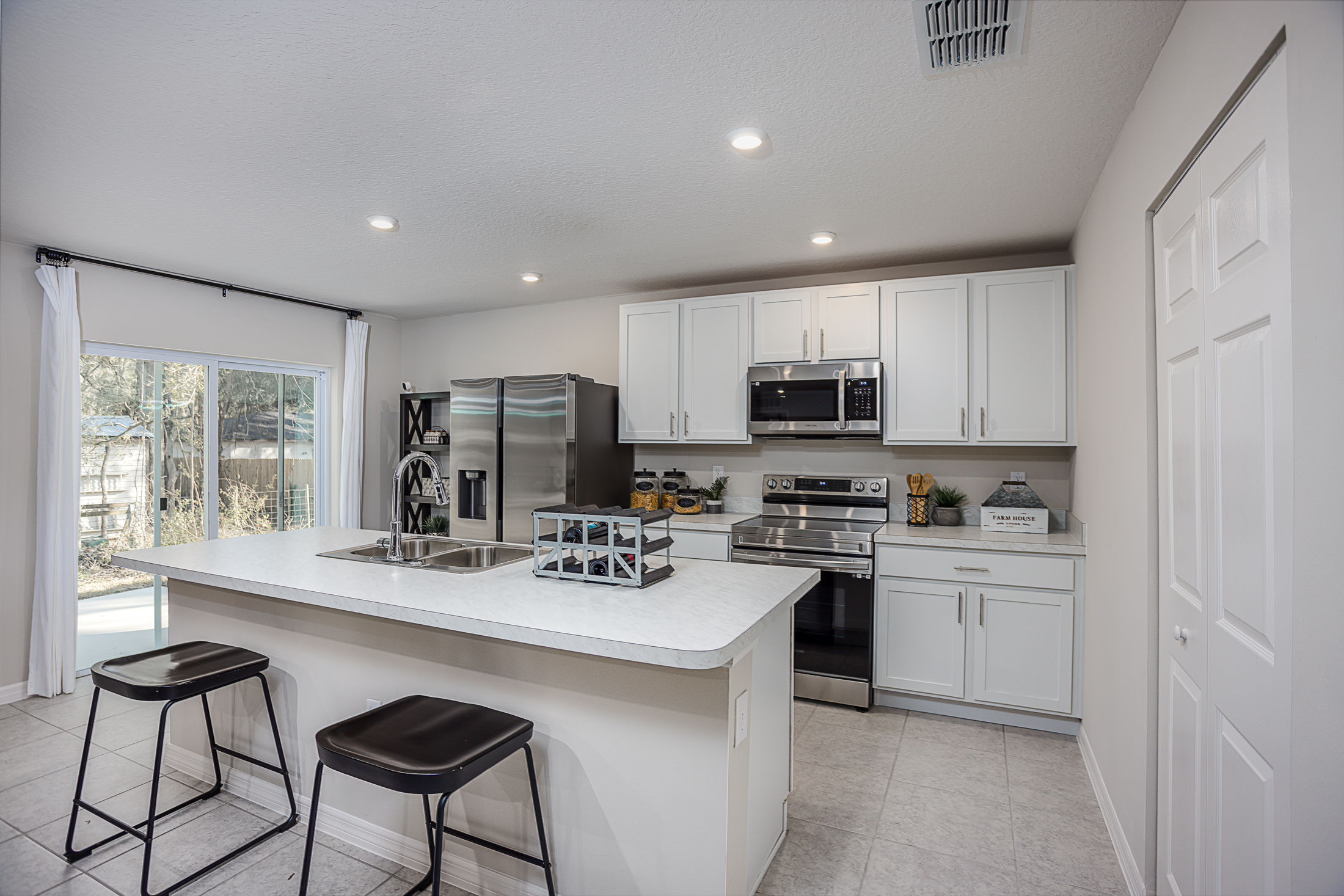 Modern kitchen with white cabinets, stainless steel appliances, and a center island with two stools.