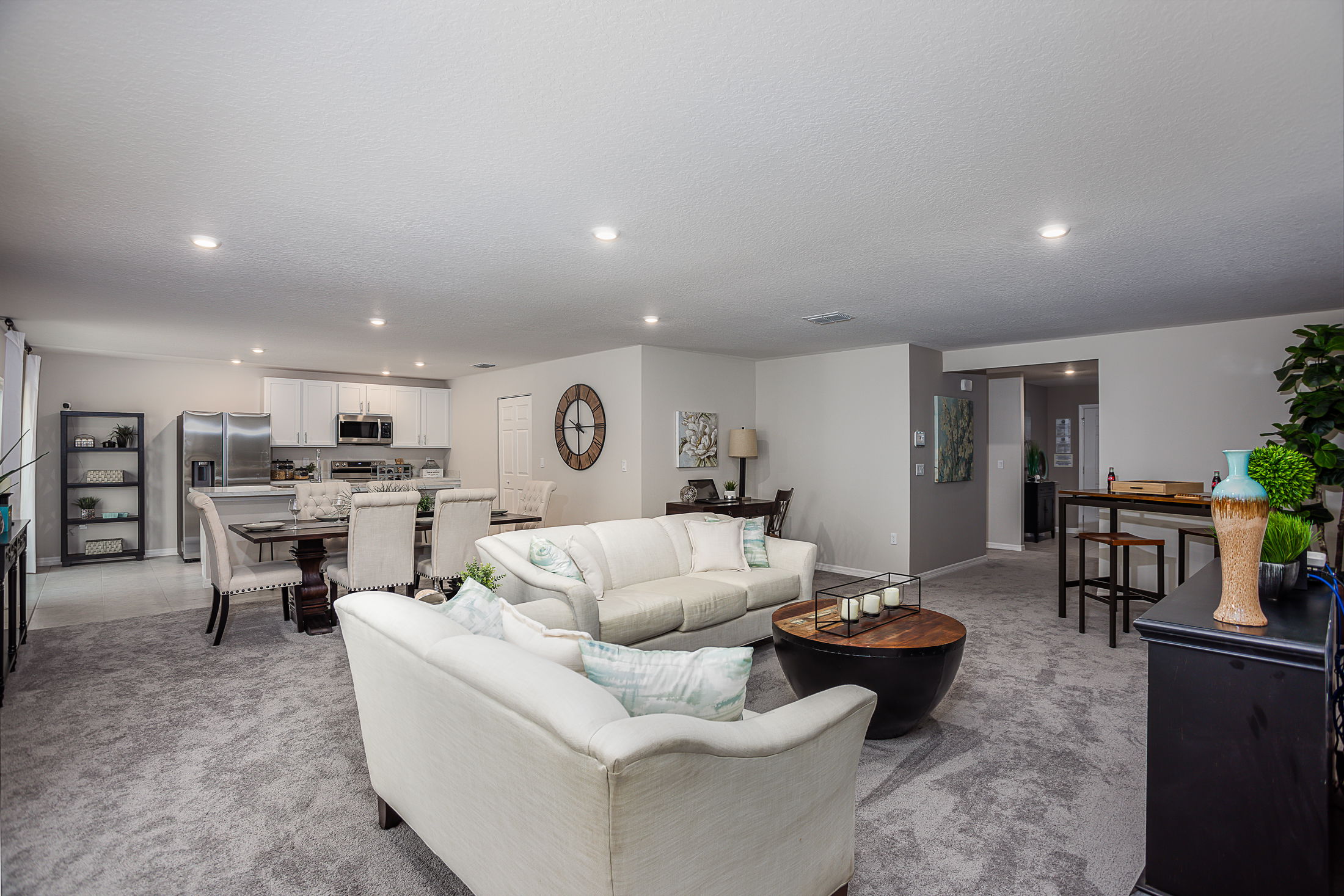 Spacious open-concept living and dining area with modern furnishings and a sleek kitchen in the background.