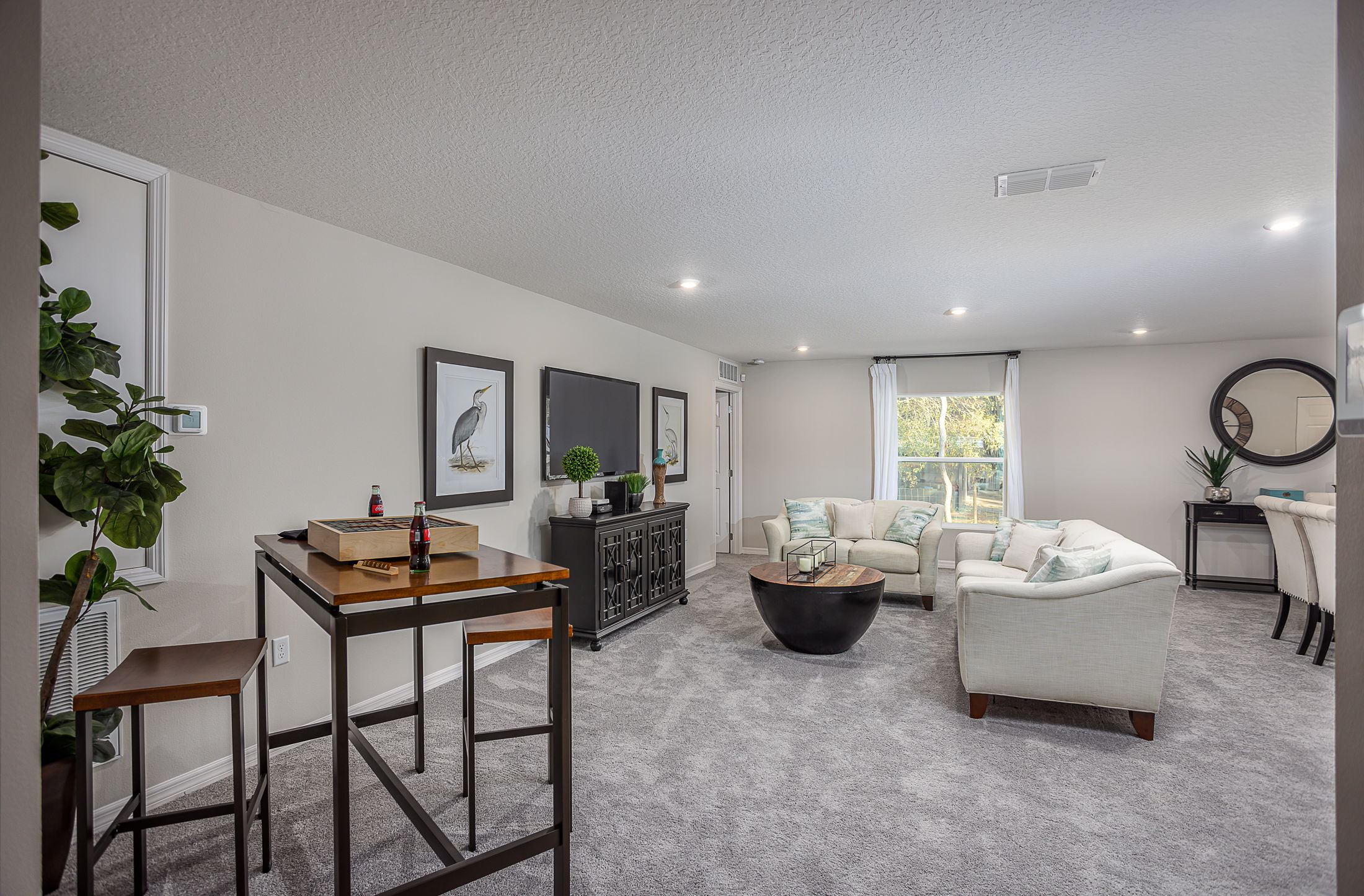 Modern living room with white sofas, dark wooden furniture, and decorative art on a neutral-colored wall.