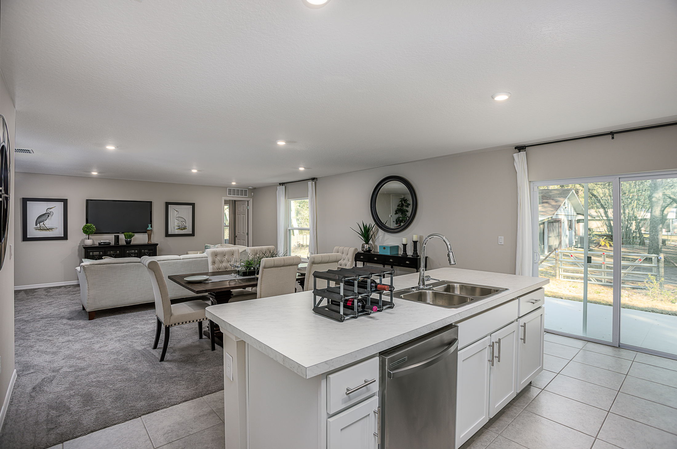 Modern open-concept living room and kitchen with elegant furnishings and large sliding glass doors.