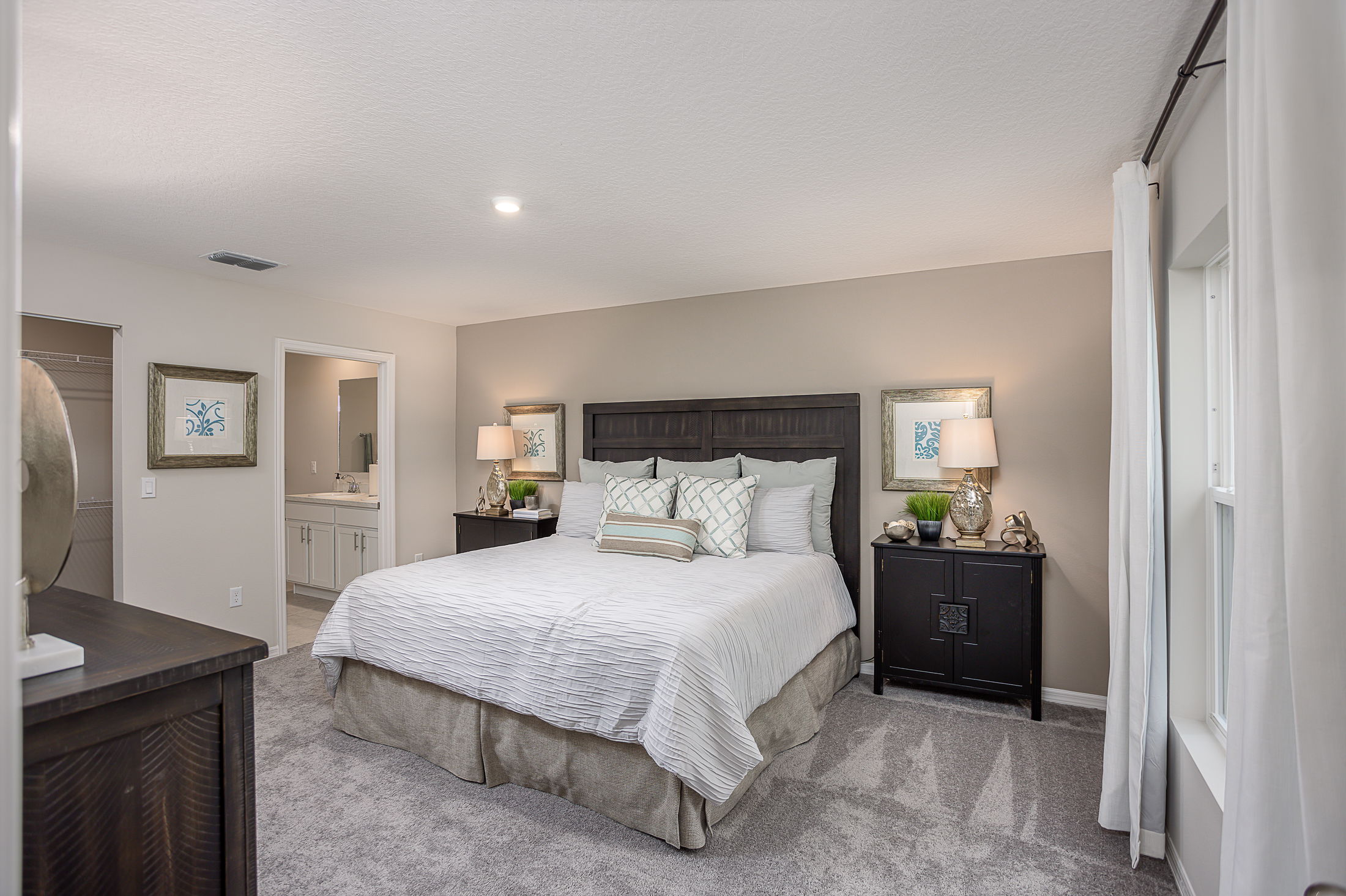 Modern bedroom with a large bed, stylish decor, and adjacent bathroom.