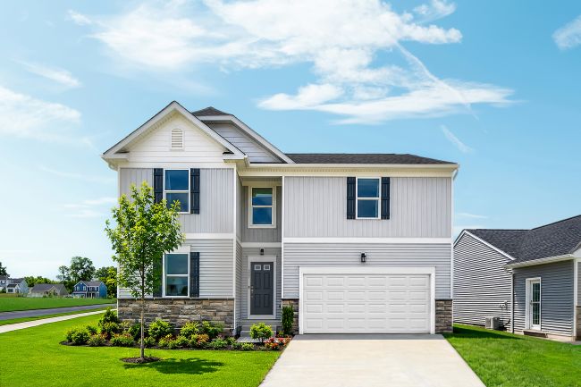 Two-story gray house with blue shutters, a white garage door, and landscaped front yard under a clear sky.