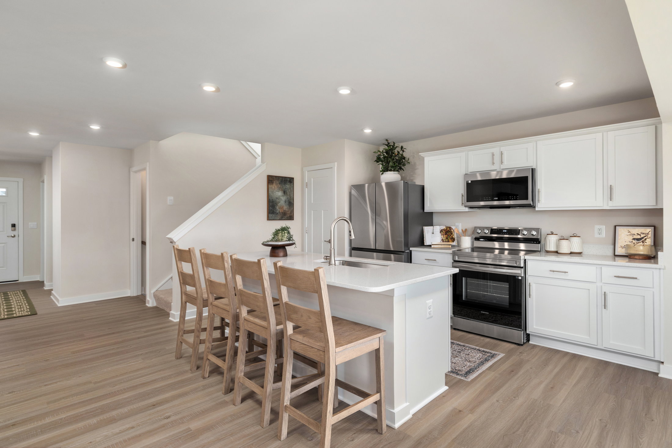 Modern kitchen with white cabinetry, stainless steel appliances, and a wooden dining table with chairs.