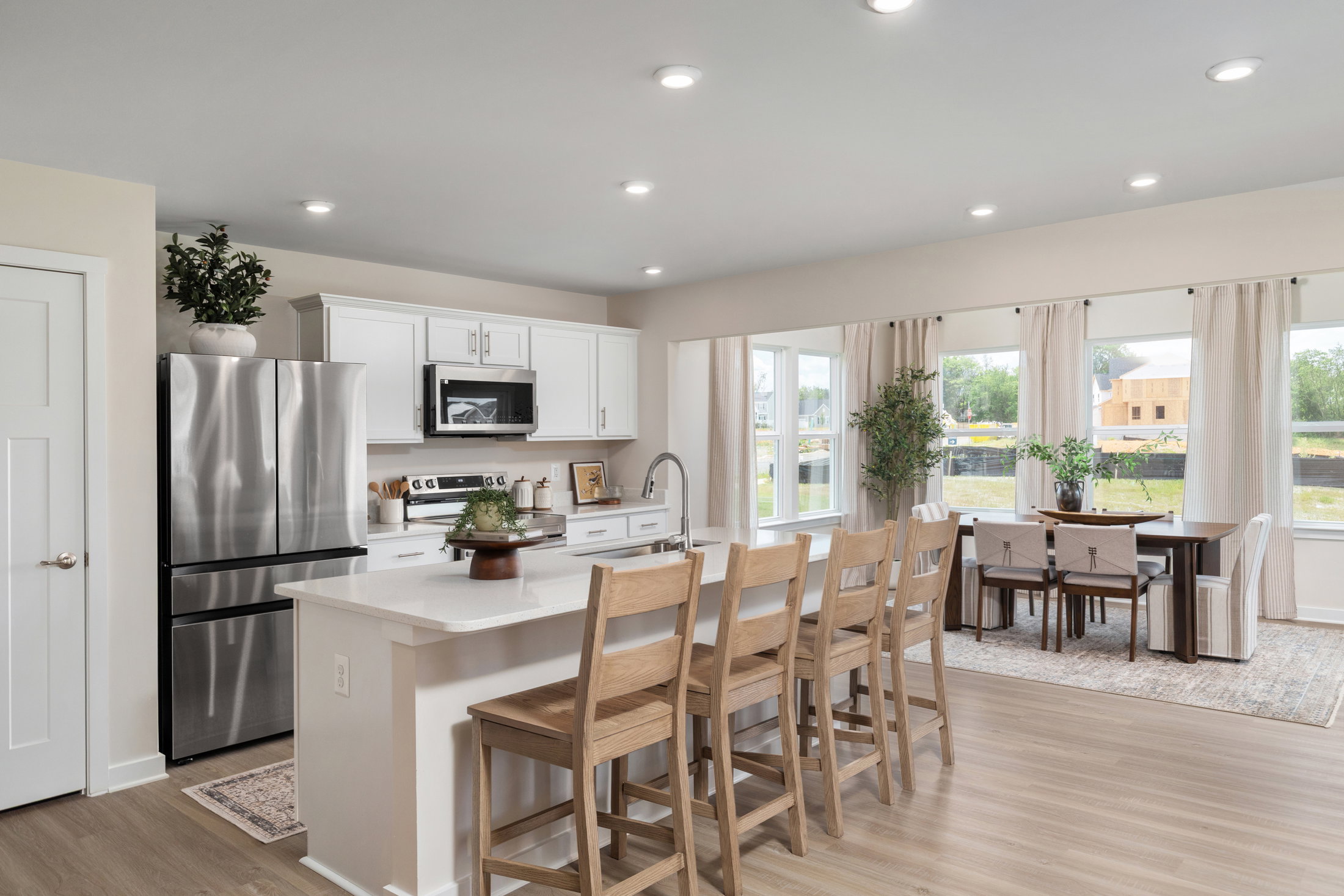 Modern kitchen featuring white cabinetry, stainless steel appliances, and a dining area with a table and chairs.