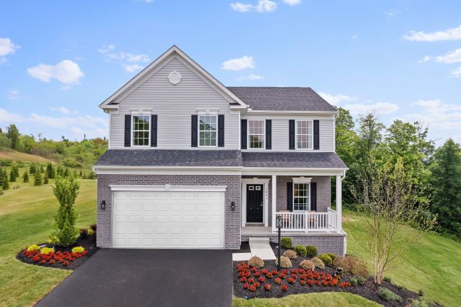 Two-story suburban house with a front porch, landscaped garden, and a two-car garage.