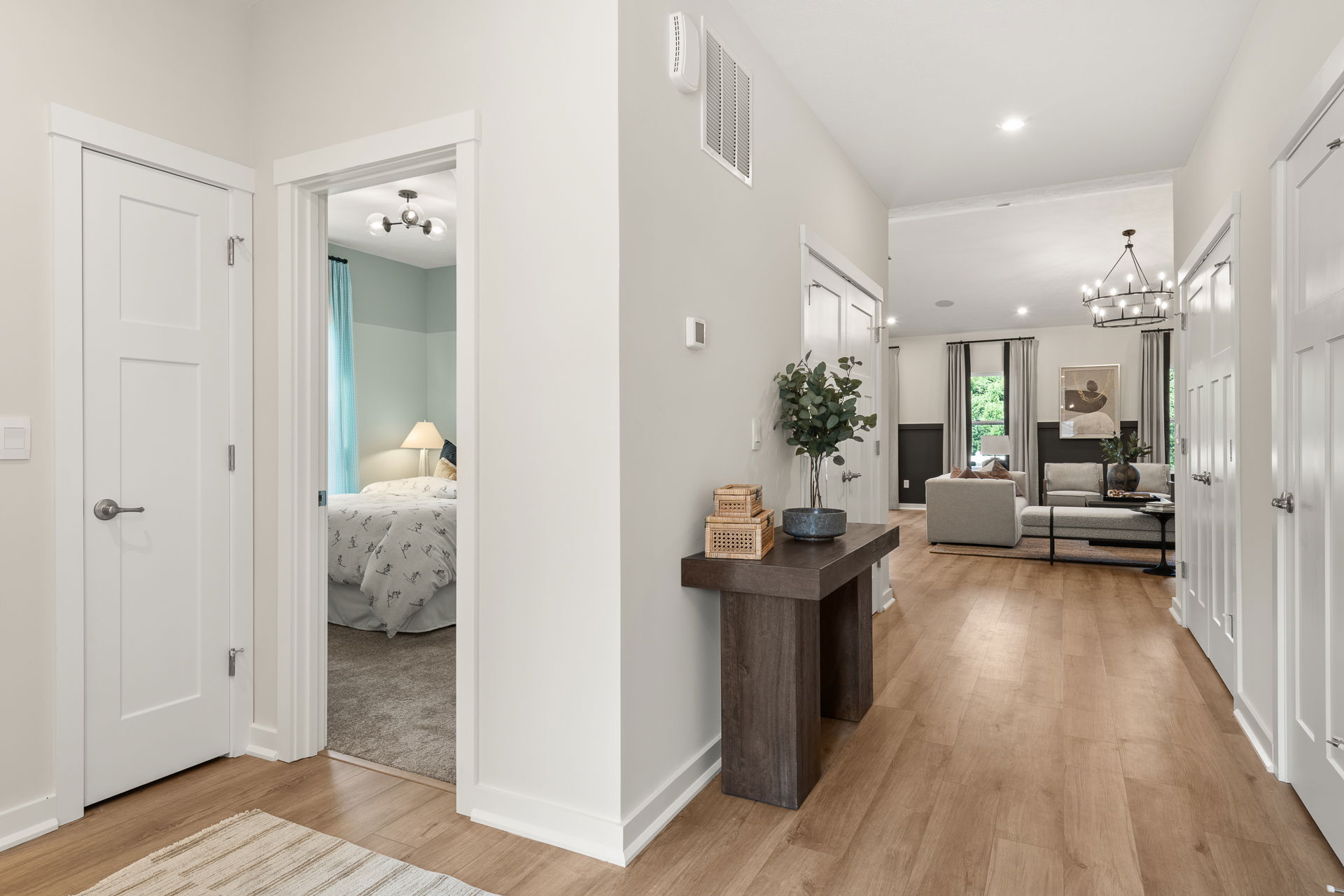 Modern home interior with a hallway leading to a cozy living room and bedroom, featuring wooden flooring and contemporary decor.