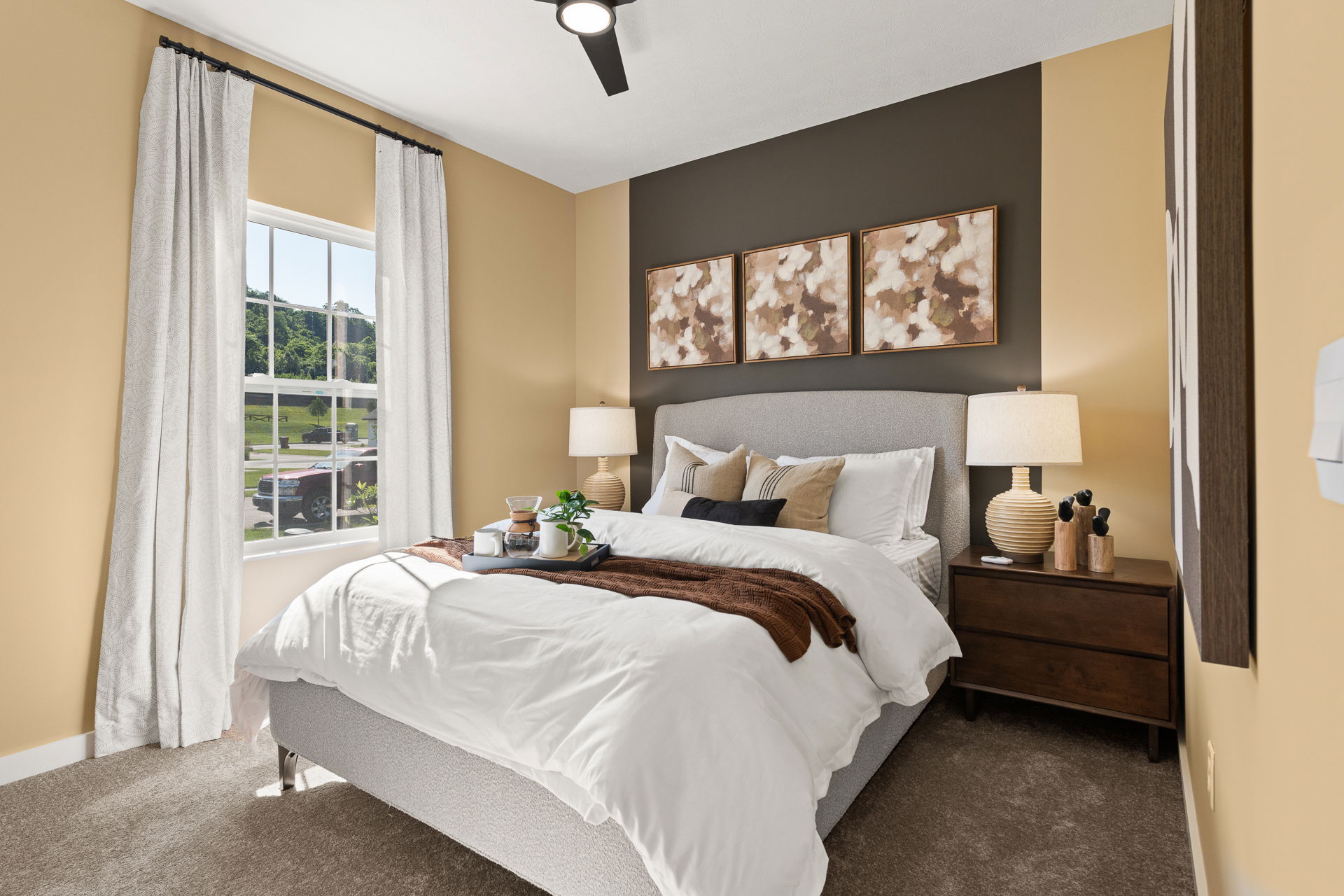 Modern bedroom interior with a cozy bed, stylish decorations, and natural light streaming through the window.