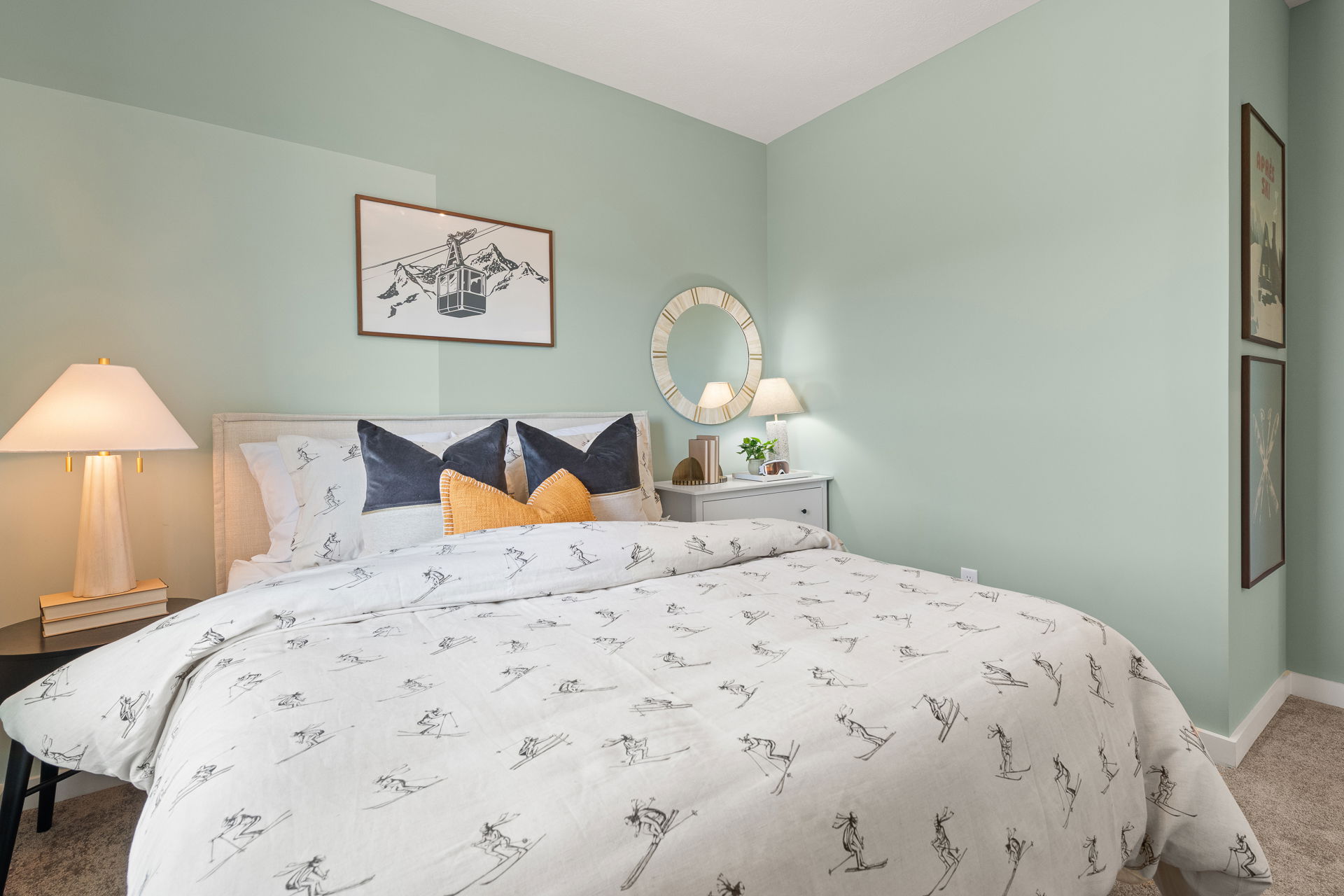 Cozy modern bedroom with a ski-themed comforter, soft lighting, and minimalist decor.