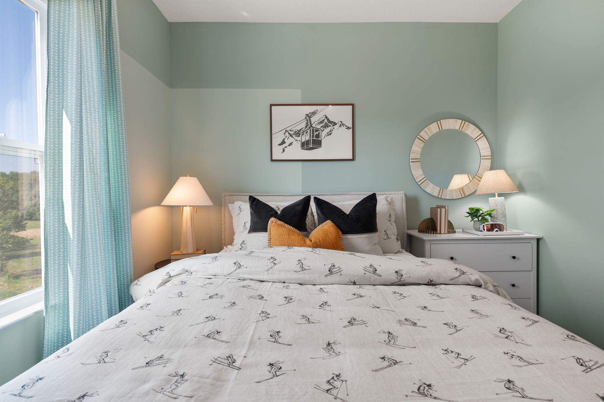 Elegant bedroom with mint green walls, ski-themed bedding, cozy pillows, and stylish bedside lamps.