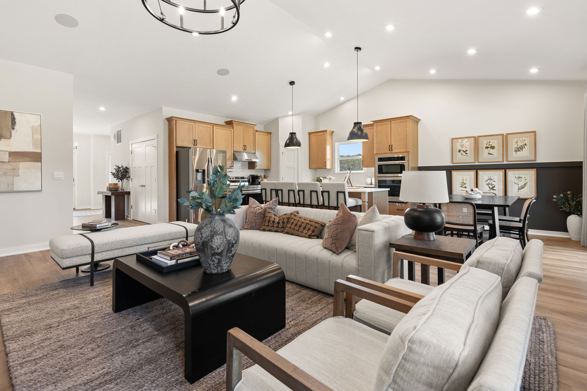 Spacious modern open-concept living room and kitchen with neutral tones, stylish decor, and wooden cabinets.