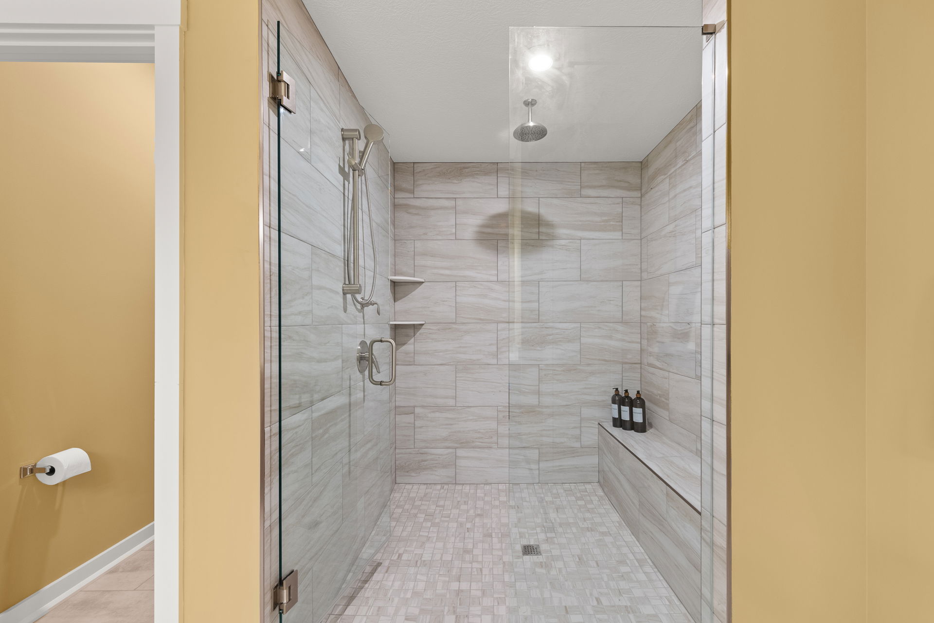 Luxurious modern walk-in shower with beige tiles, sleek fixtures, and a glass door.