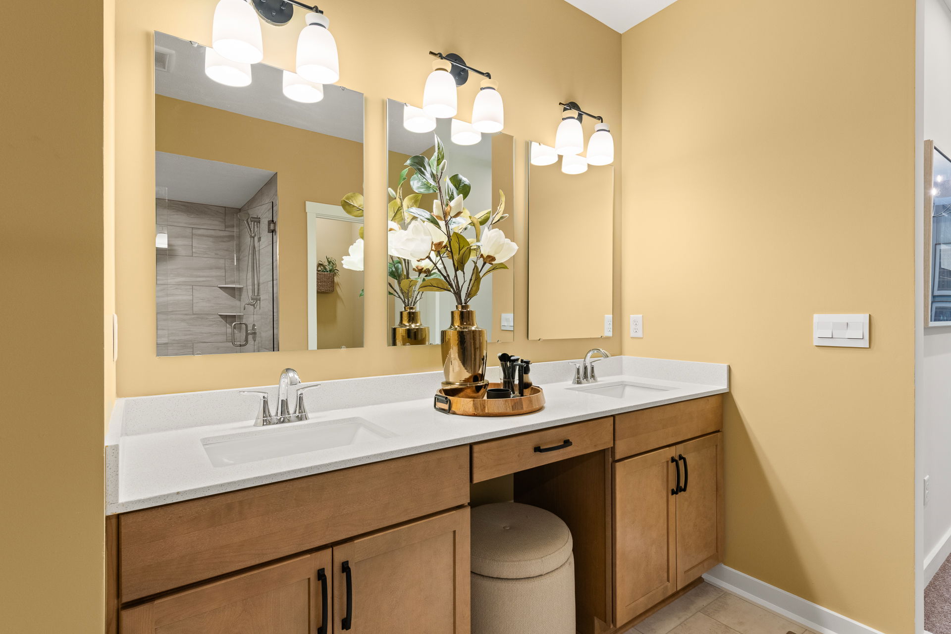 Modern bathroom vanity with dual sinks, wooden cabinets, and decorative accents against a warm yellow wall.