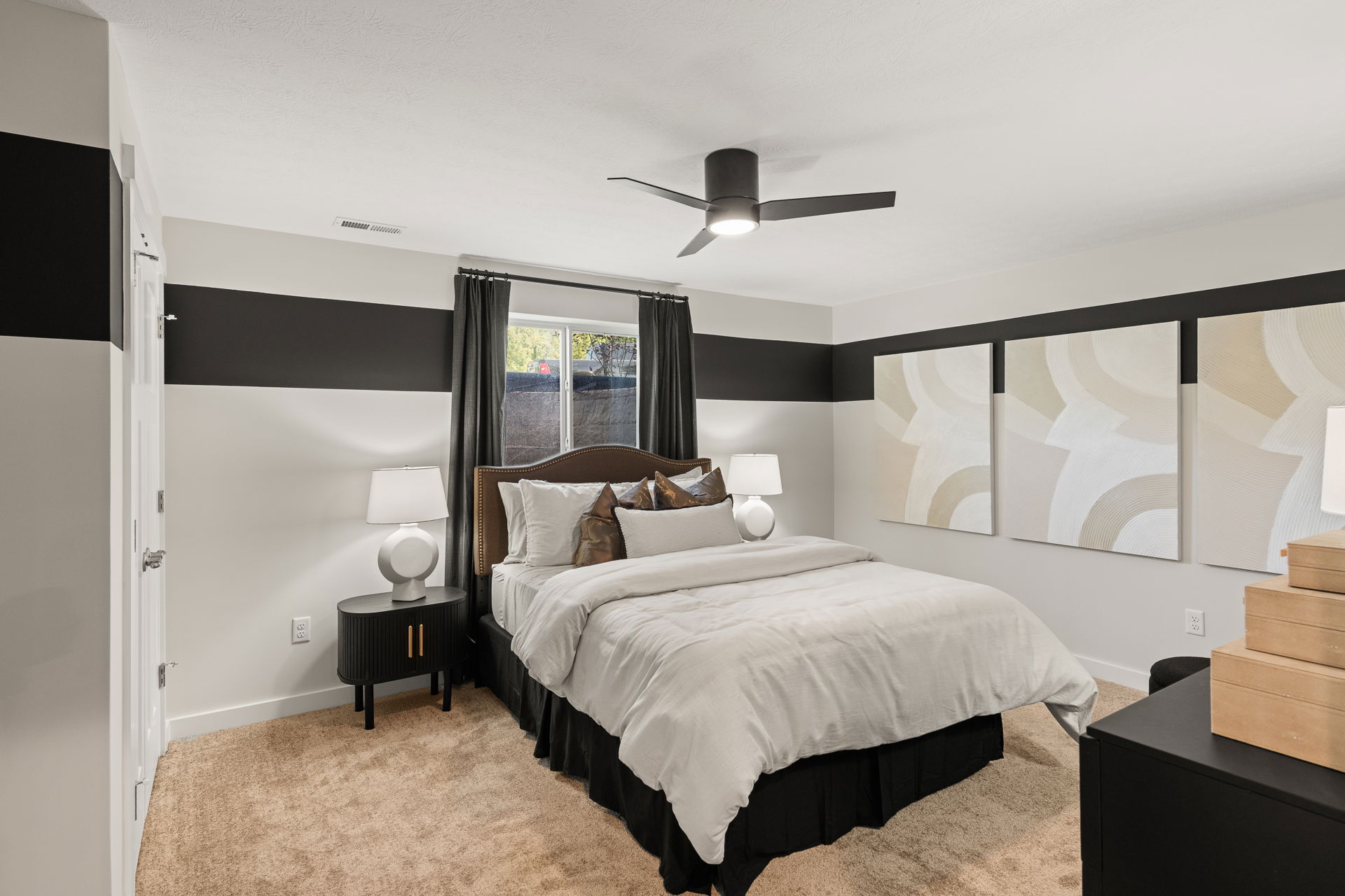 Modern minimalist bedroom with a cozy bed, abstract wall art, and sleek black and white decor.