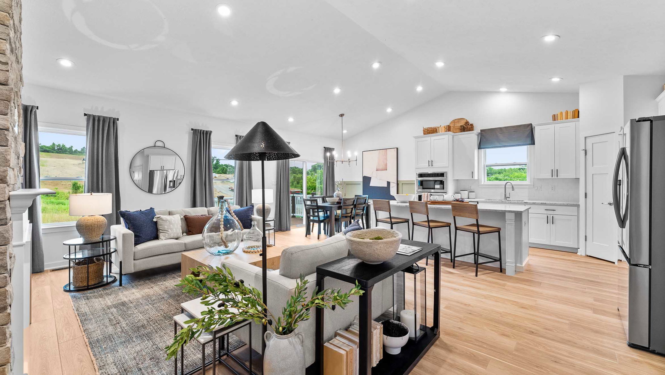 Modern open-concept living room and kitchen with white cabinets, stylish decor, and abundant natural light.
