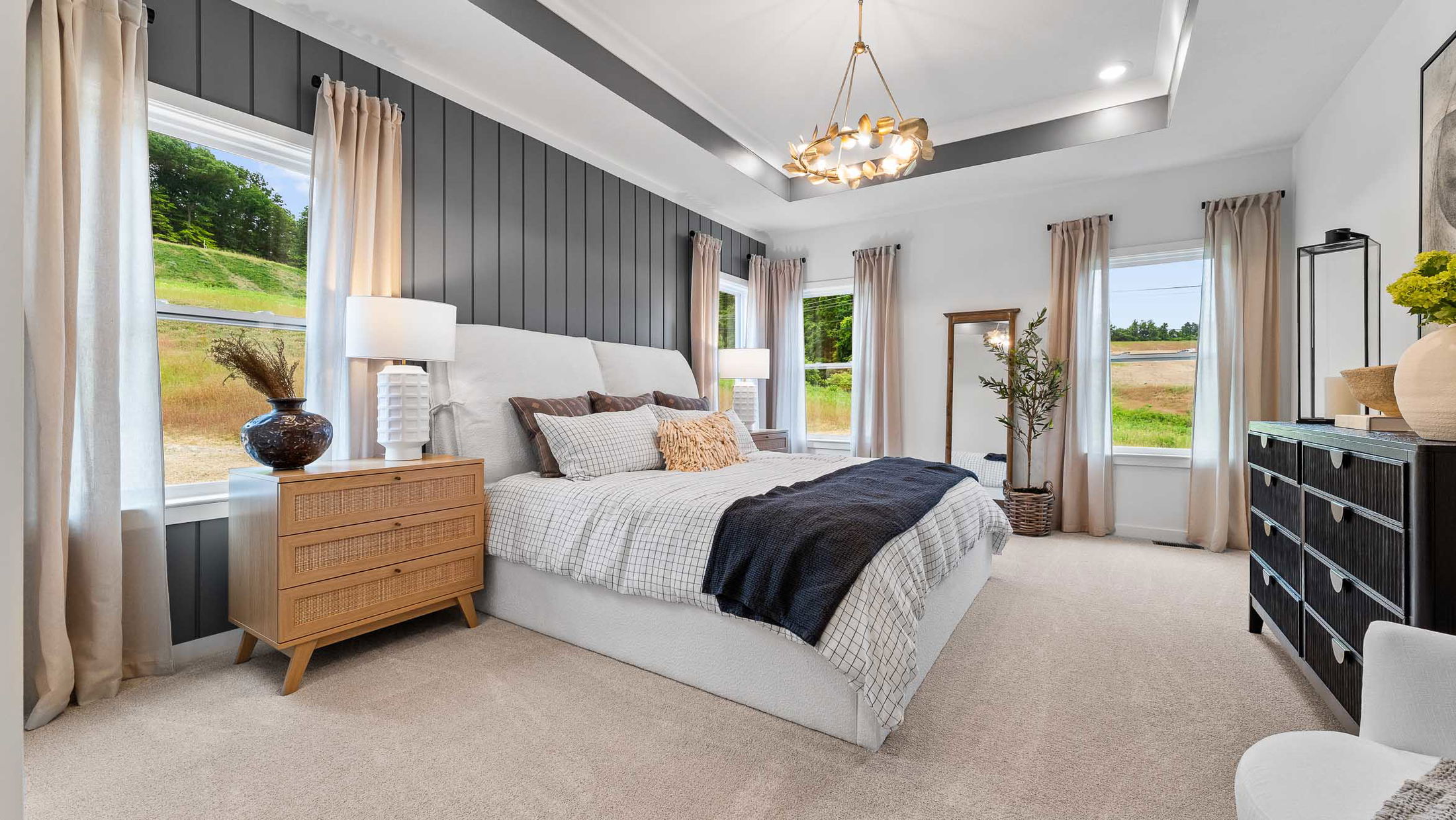 Modern bedroom with a cozy bed, stylish lighting, and large windows showcasing a scenic outdoor view.