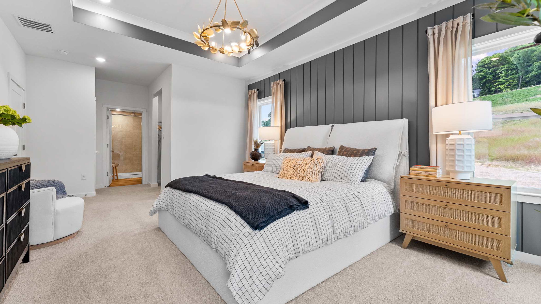 Modern bedroom with a cozy bed, elegant chandelier, and stylish gray accent wall.