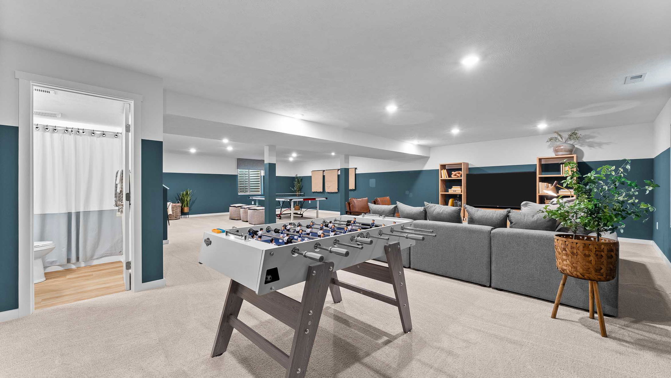 Spacious modern basement game room with a foosball table, entertainment area, and stylish décor.