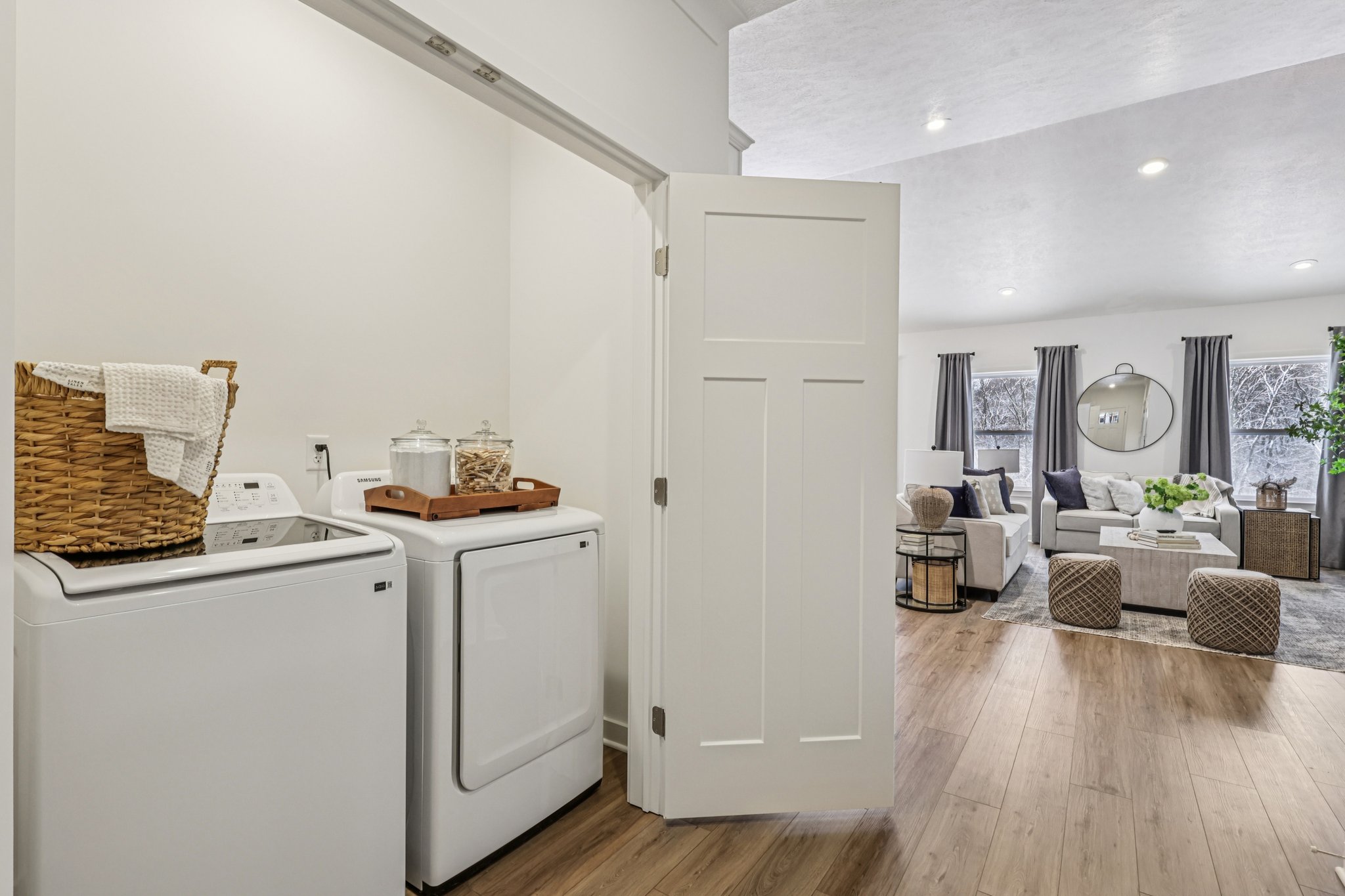 Laundry area with a washer and dryer, leading to a modern living room with a comfortable seating arrangement and decorative elements.