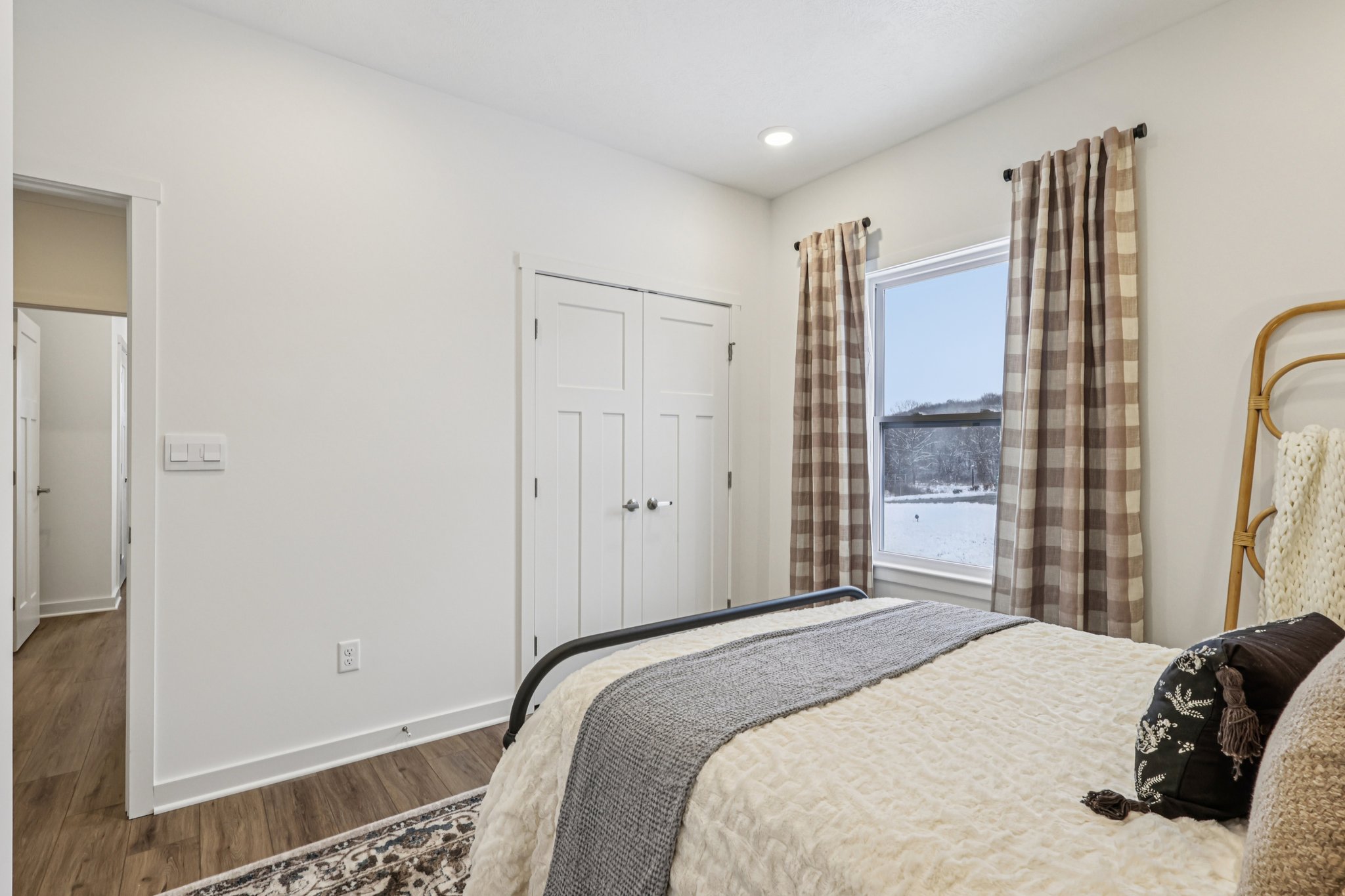 Cozy bedroom with a bed, patterned curtains, and a view of snow outside the window.