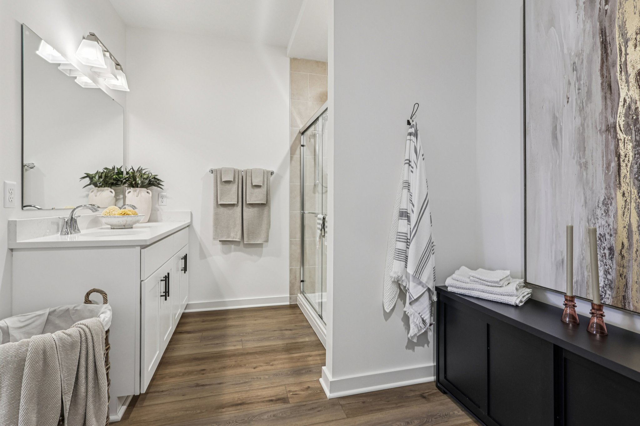 Modern bathroom featuring a glass shower, white cabinetry, and decorative towels on a rack.