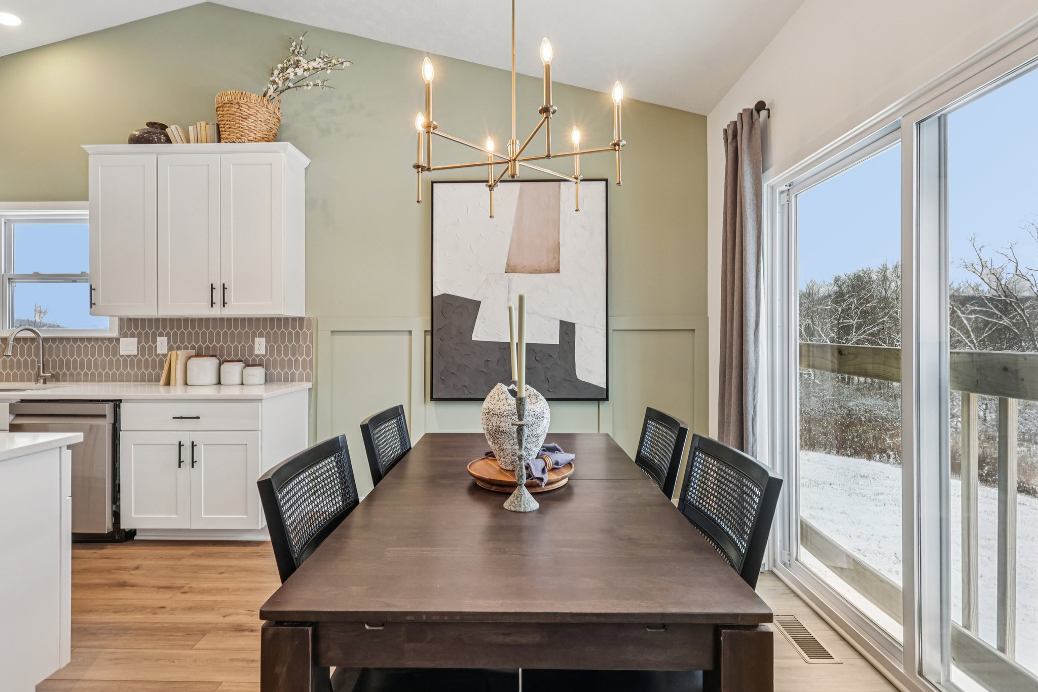 A modern dining area featuring a wooden table, black chairs, and a large abstract artwork on the wall.