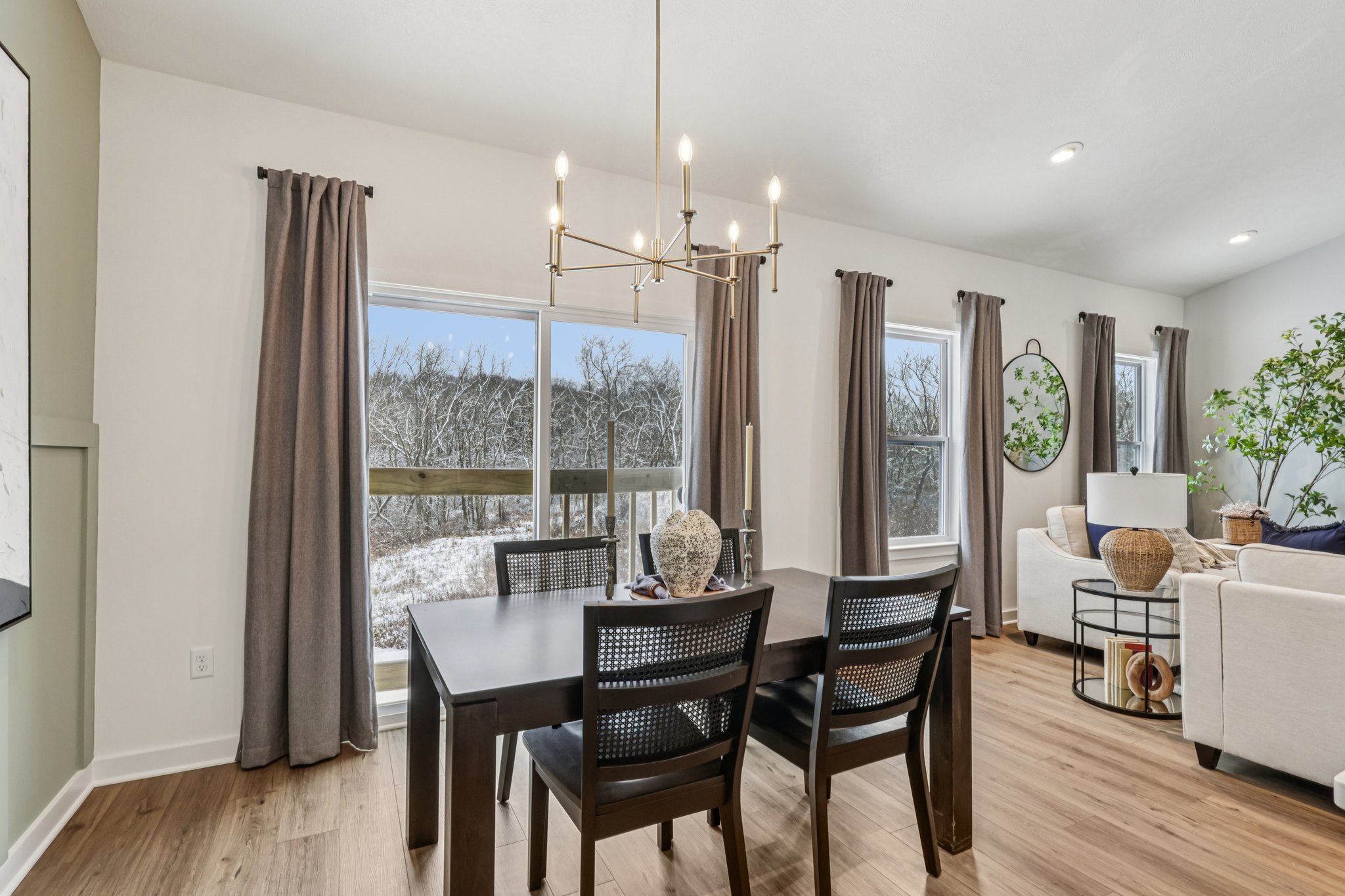 Stylish dining area featuring a dark wooden table, black chairs, and large windows with a view of snowy trees.