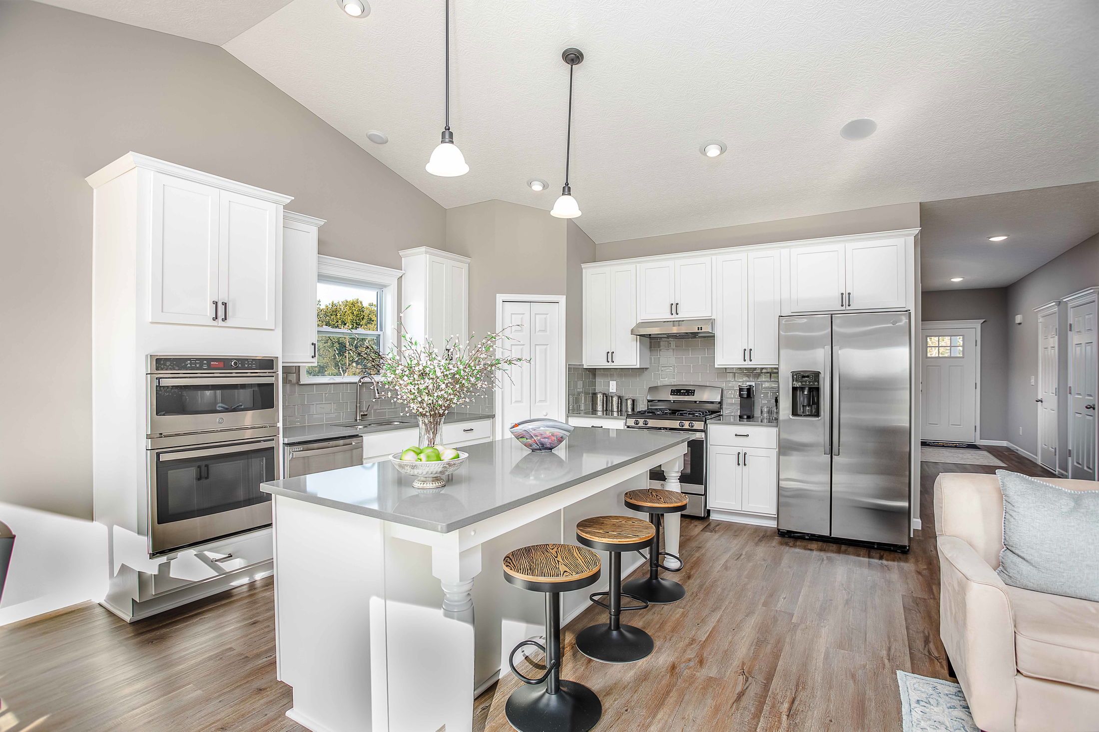 Modern kitchen with white cabinetry, stainless steel appliances, and a spacious island with barstools.