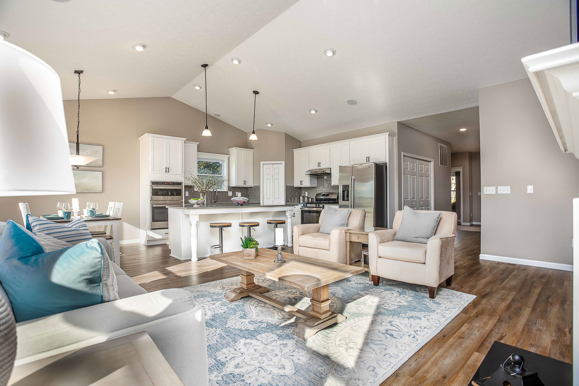 Modern open-concept living room and kitchen with beige walls, white cabinetry, and hardwood flooring.