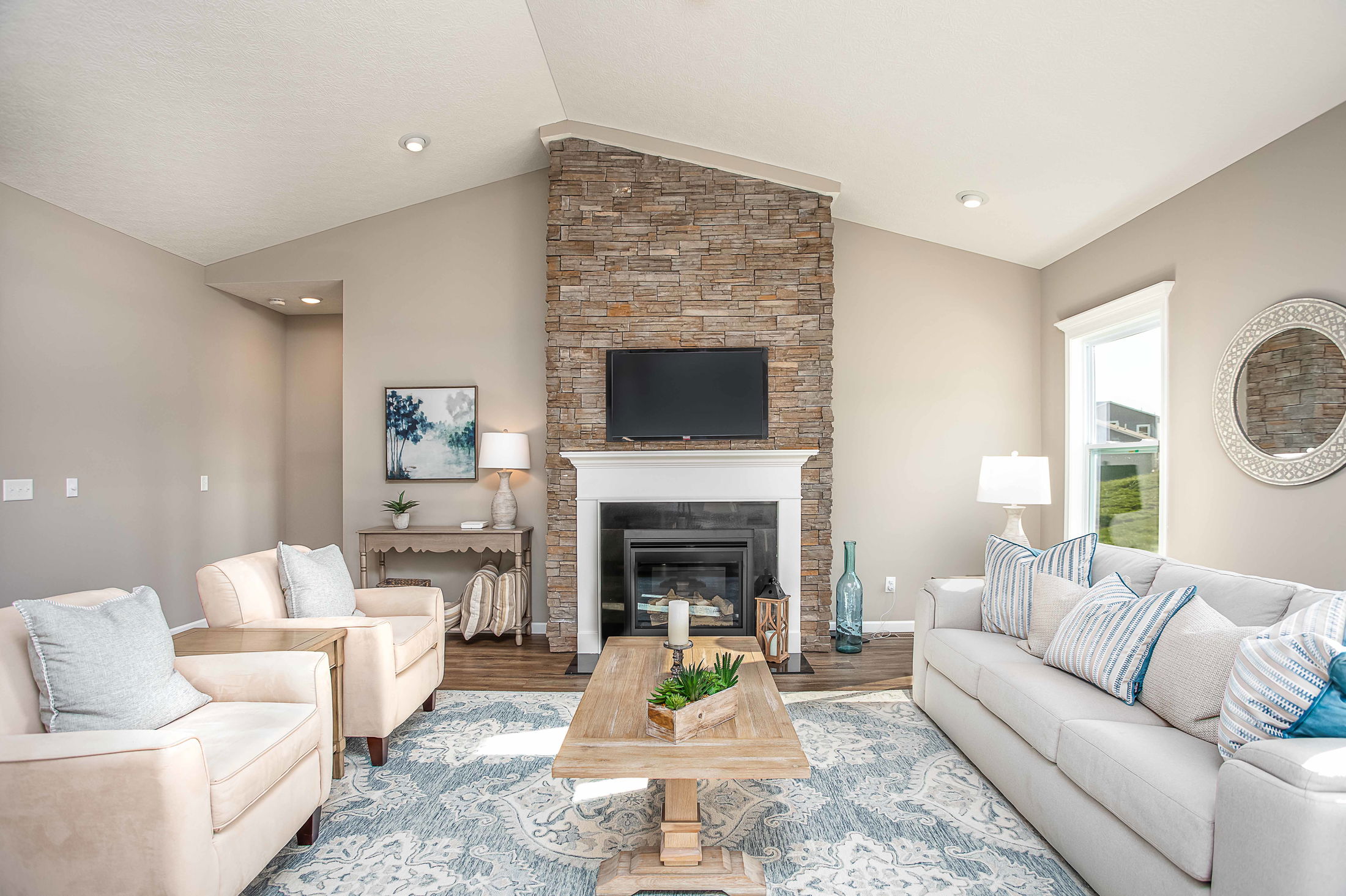 Modern living room with stone fireplace, comfy sofas, and elegant decor for a cozy ambiance.