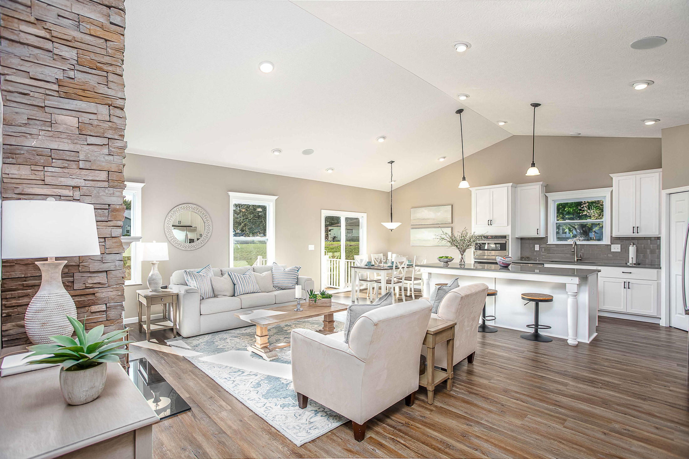 Bright, open-concept living room and kitchen with modern decor, white cabinets, and stylish furnishings.