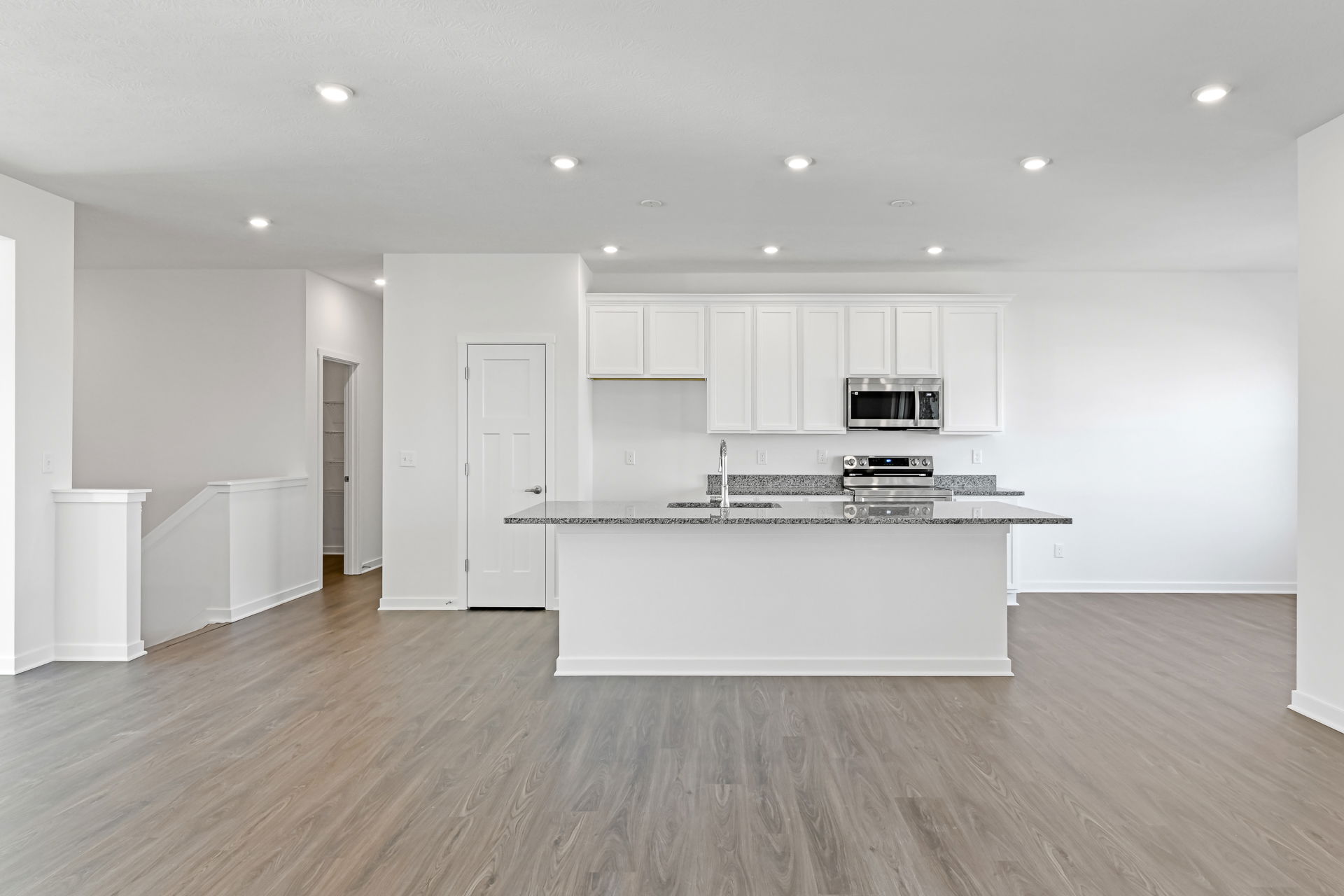 Modern kitchen interior with white cabinetry, stainless steel appliances, and hardwood flooring.