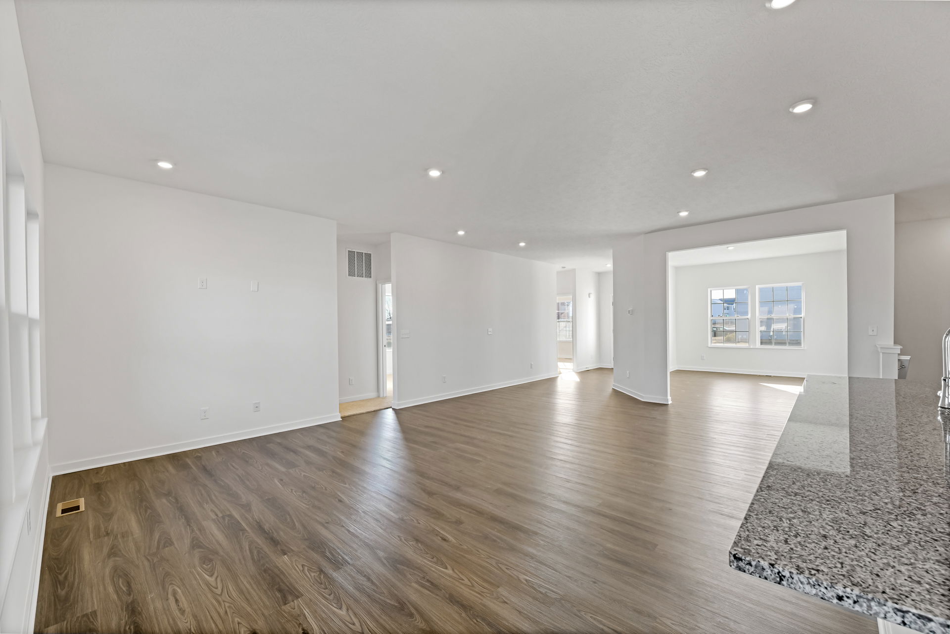 Spacious modern open-concept living area with hardwood floors and abundant natural light streaming through large windows.