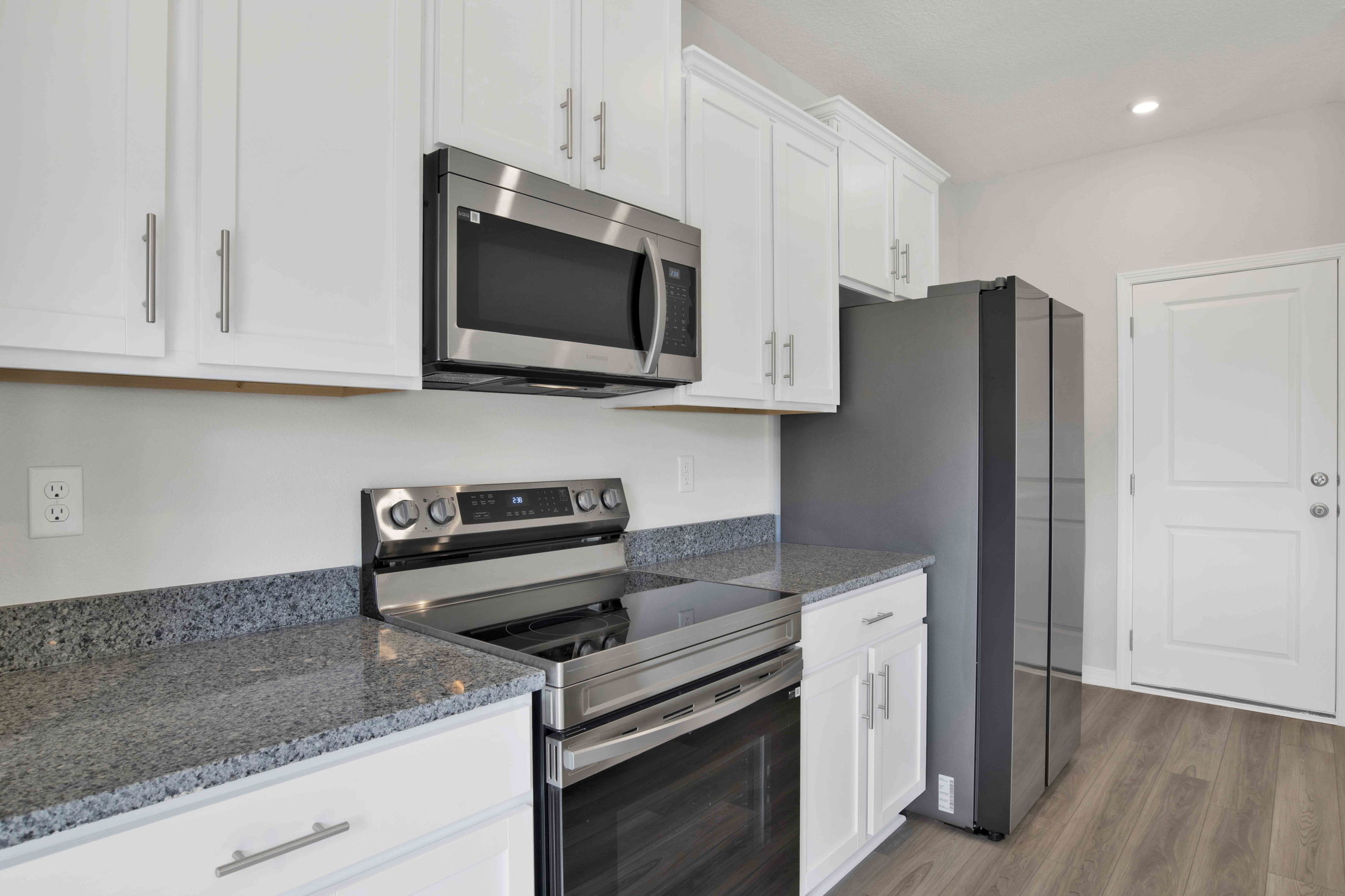 Modern kitchen with stainless steel appliances, white cabinets, and granite countertops.
