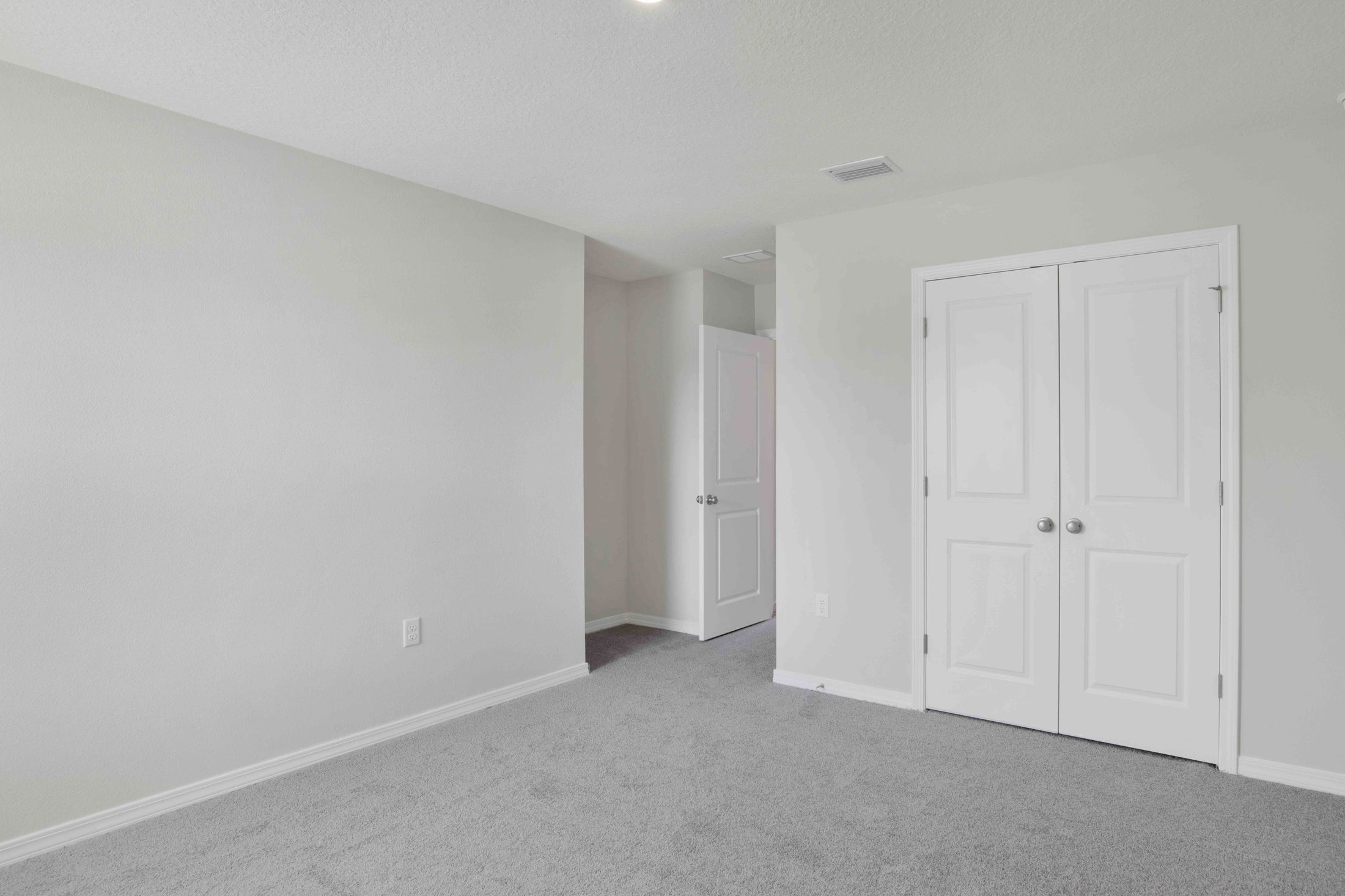 Empty room with gray carpet, white walls, and two white doors.