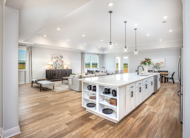 Spacious open-concept kitchen and living room with a large white island, wooden floors, and modern decor.