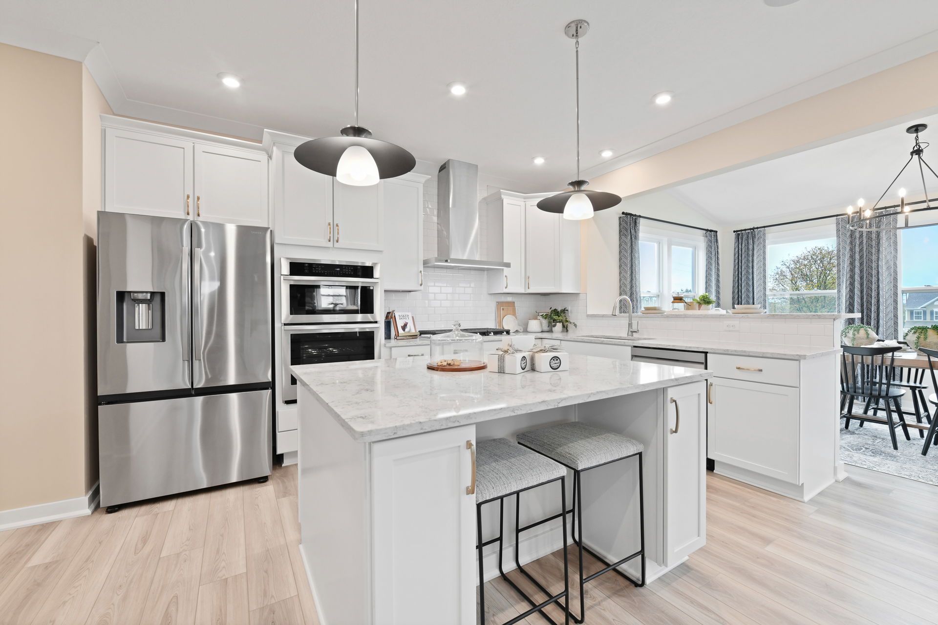 Modern kitchen with white cabinets, stainless steel appliances, and a large marble island with pendant lighting.
