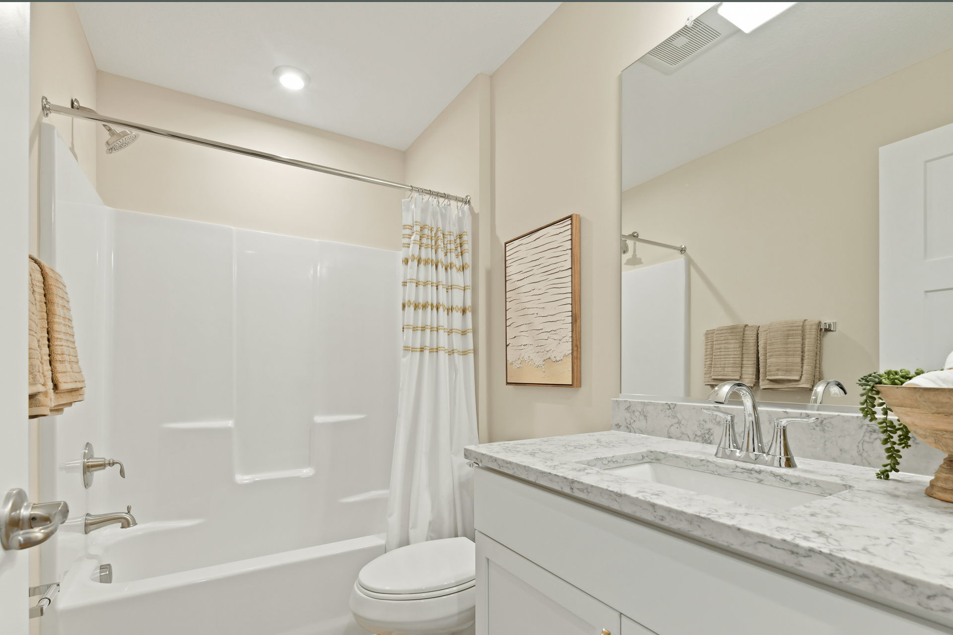 Modern bathroom with marble countertop, white bathtub, and stylish decor under bright lighting.