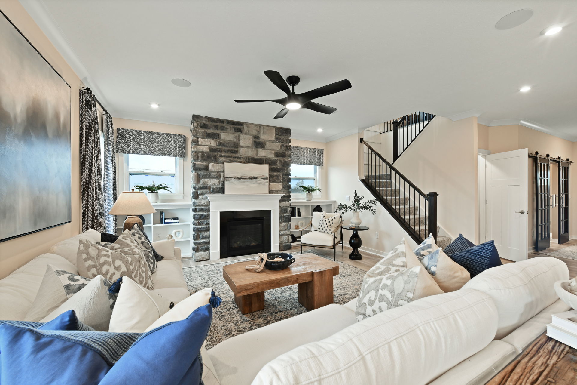 Modern living room with a stone fireplace, cozy seating, and stylish decor.