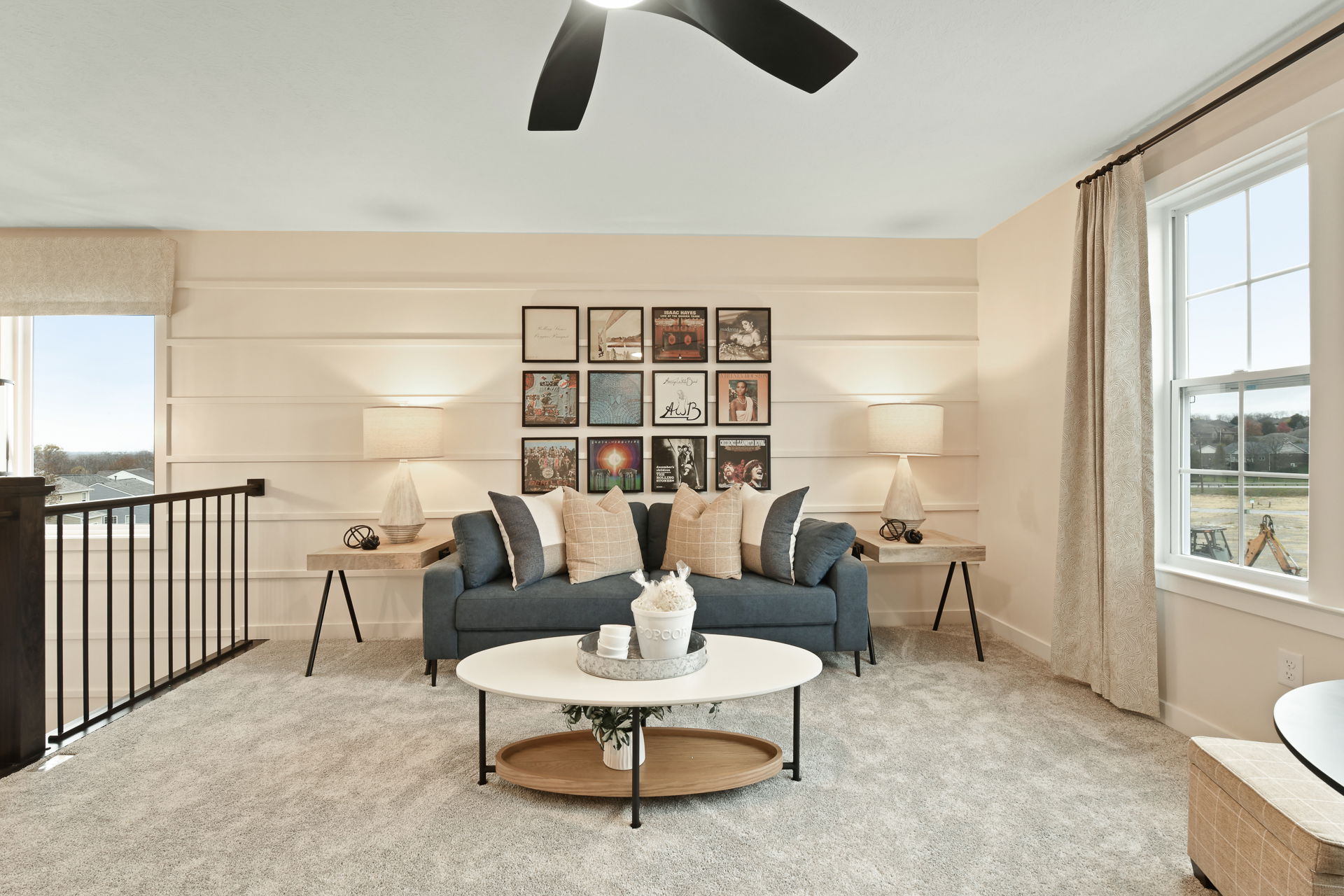 Stylish living room with a blue sofa, decorative pillows, modern artwork, and a round coffee table complemented by warm lighting.