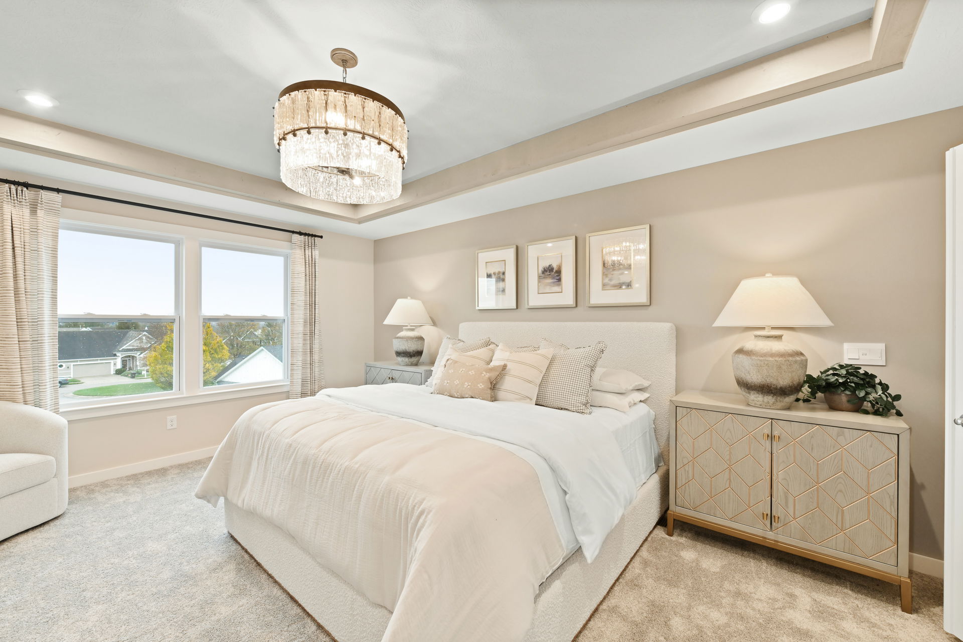 Elegant bedroom with a large bed, plush bedding, modern chandelier, and decorative artwork on the walls.