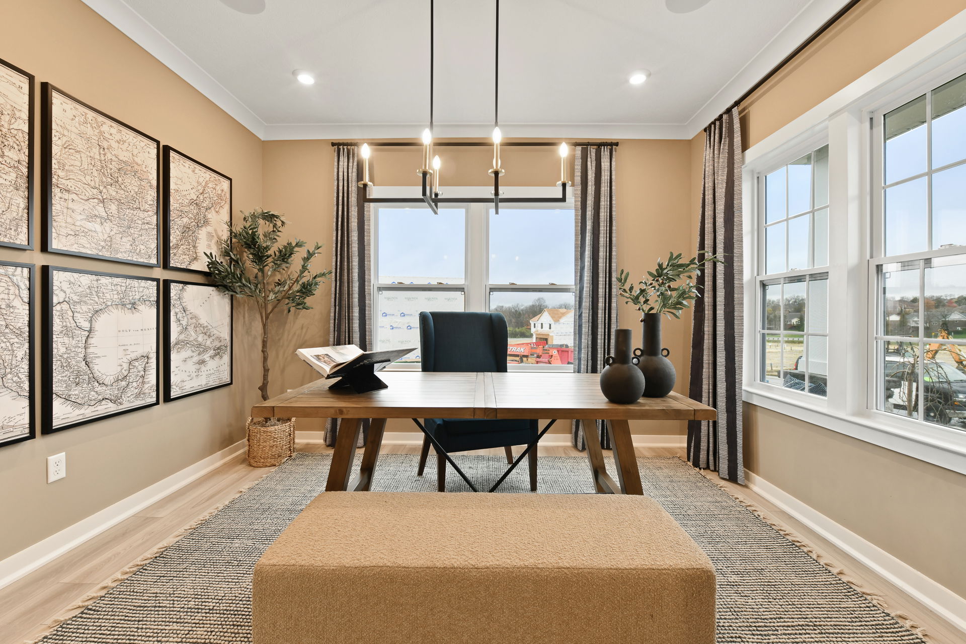 Stylish home office with modern wooden desk, large wall maps, and ample natural light from double windows.