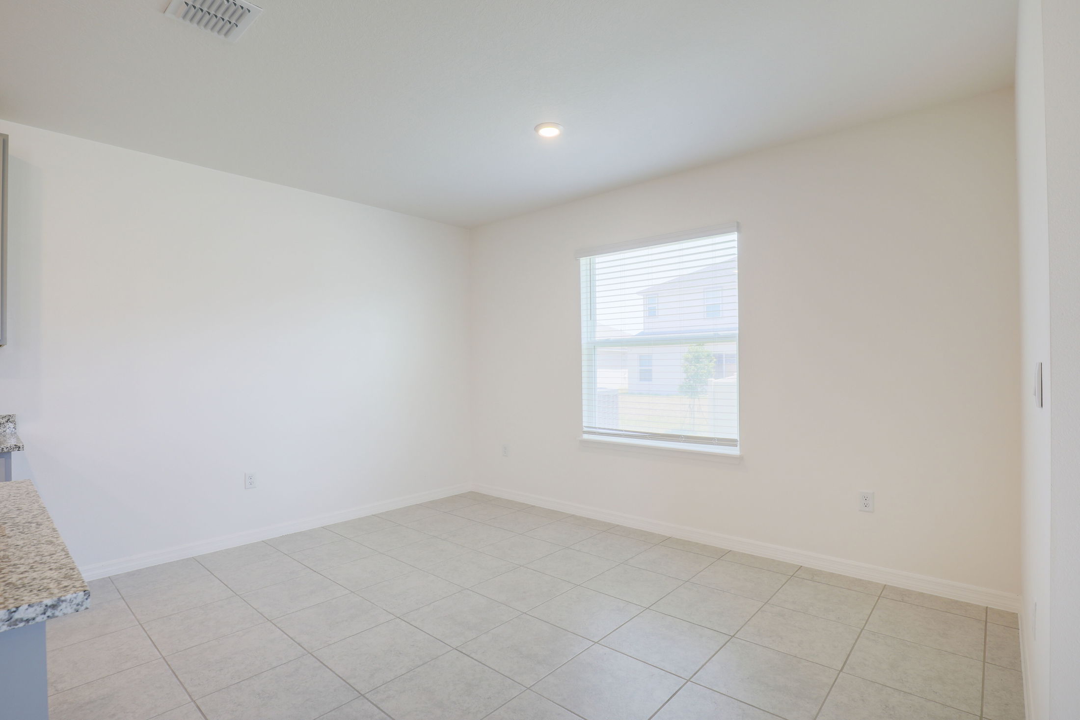 Bright, empty room with tiled flooring, white walls, and a window with blinds.