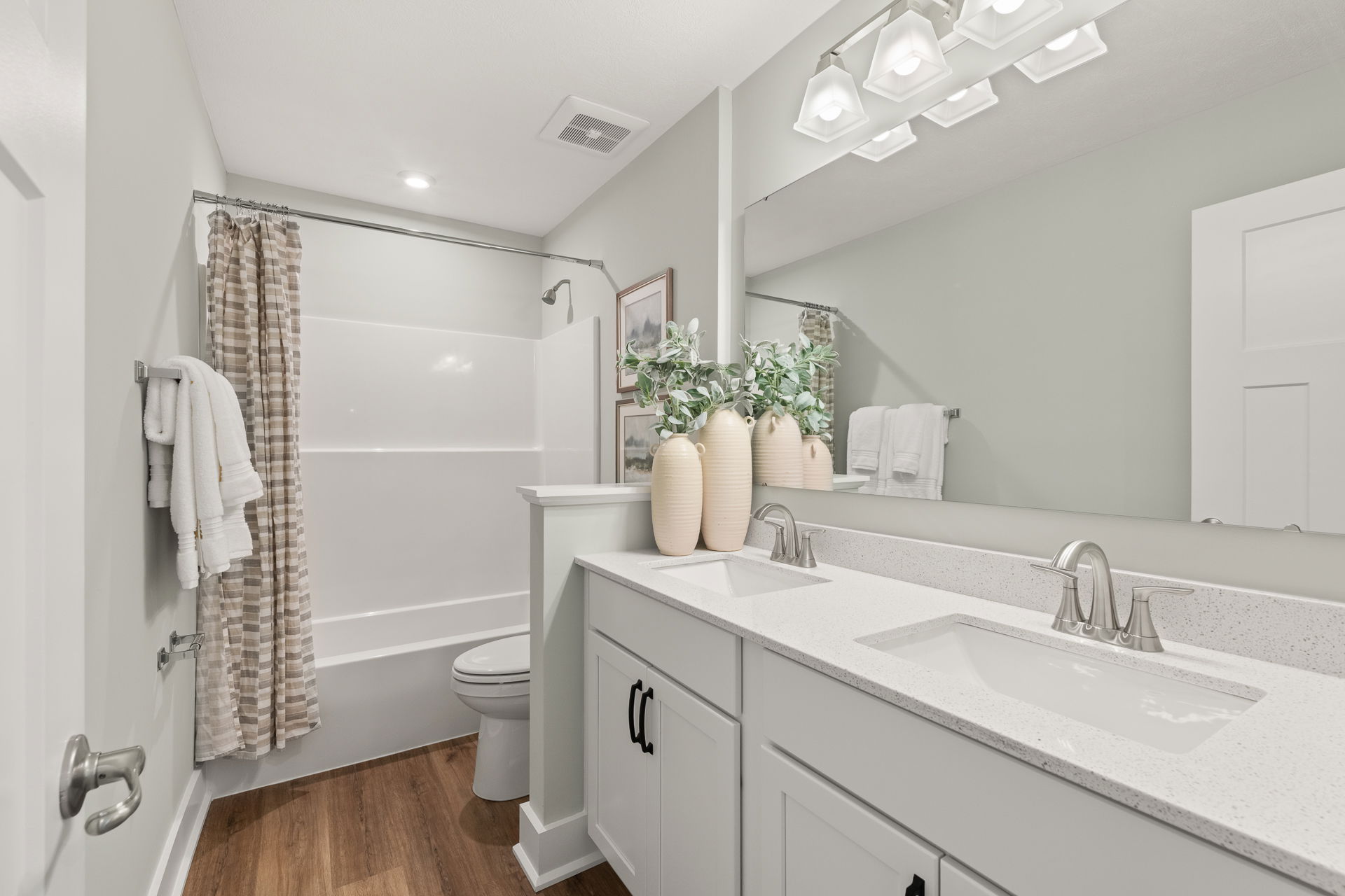 Modern bathroom with a white double vanity, mirror, and shower featuring a patterned curtain.